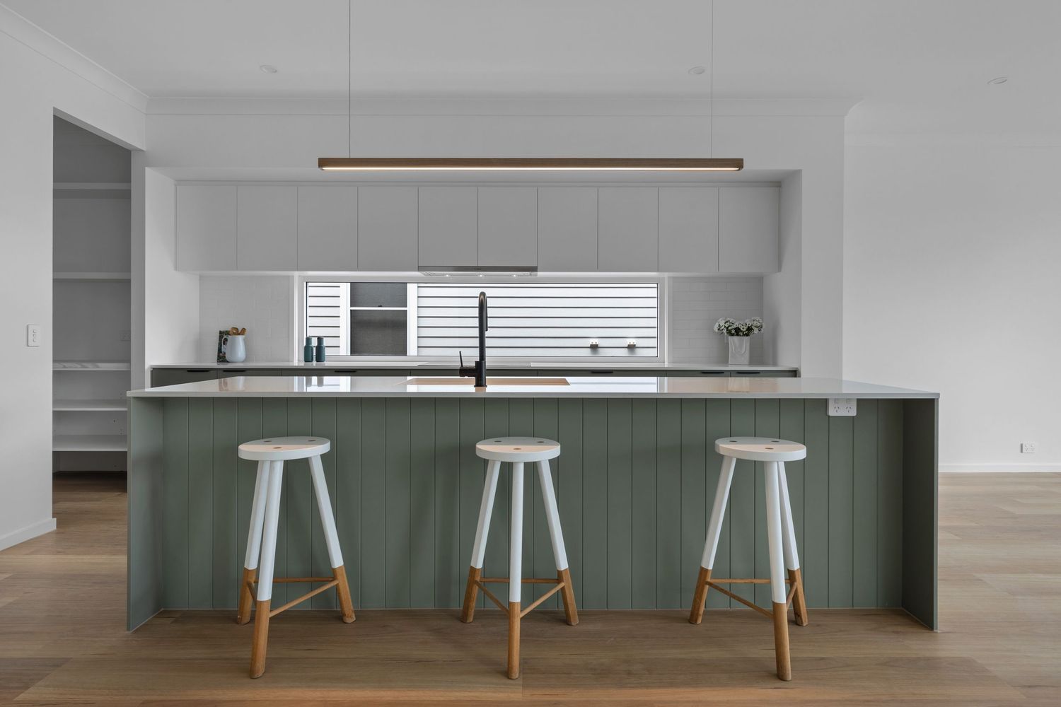 Interior photograph of a kitchen with green cabinetry and bar seating.