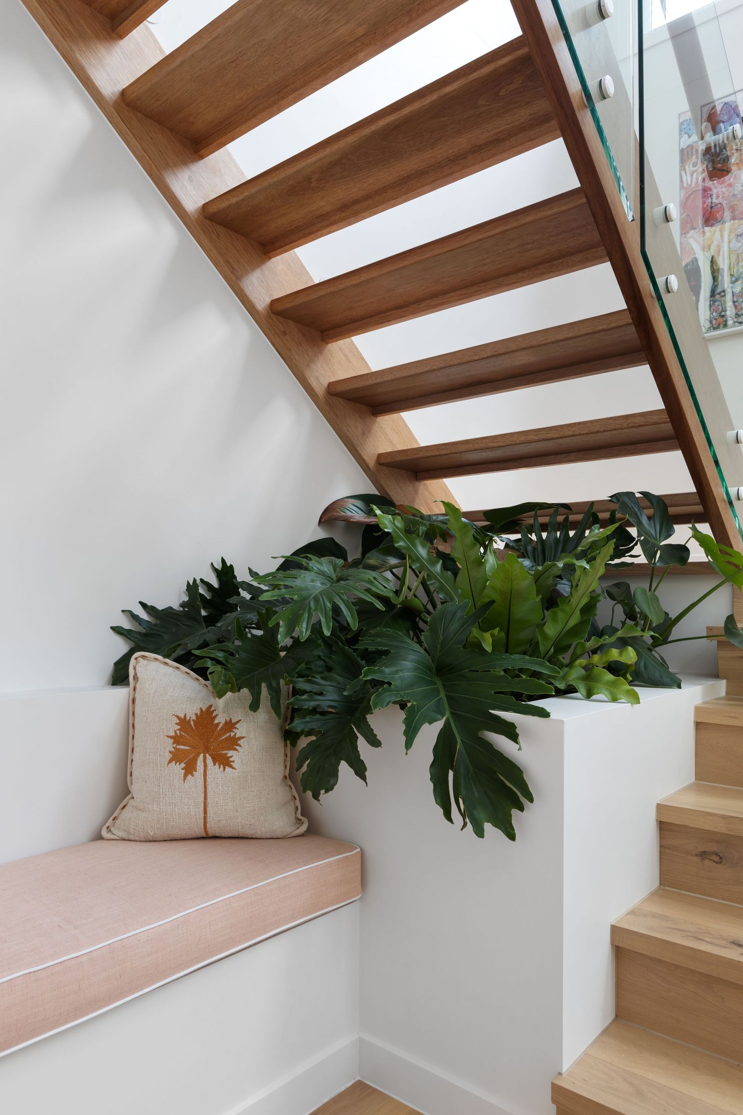 Interior photograph of a staircase and entryway with potted plant.