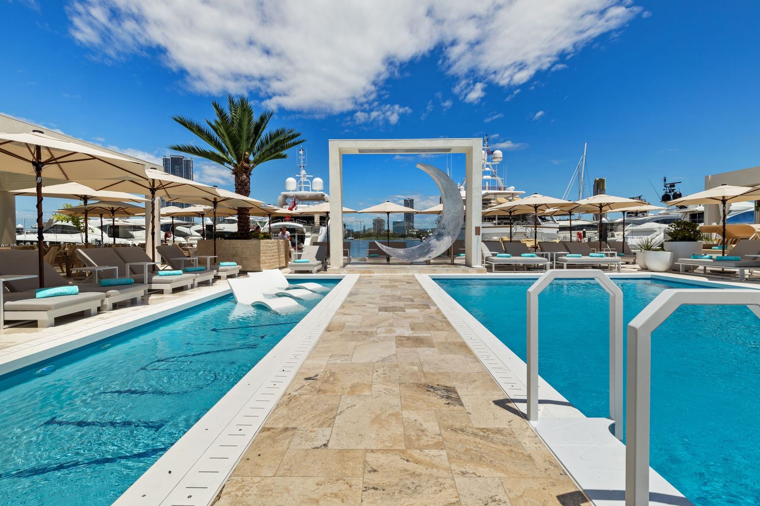 Photograph of a resort-style swimming pool with palm trees and pergola.