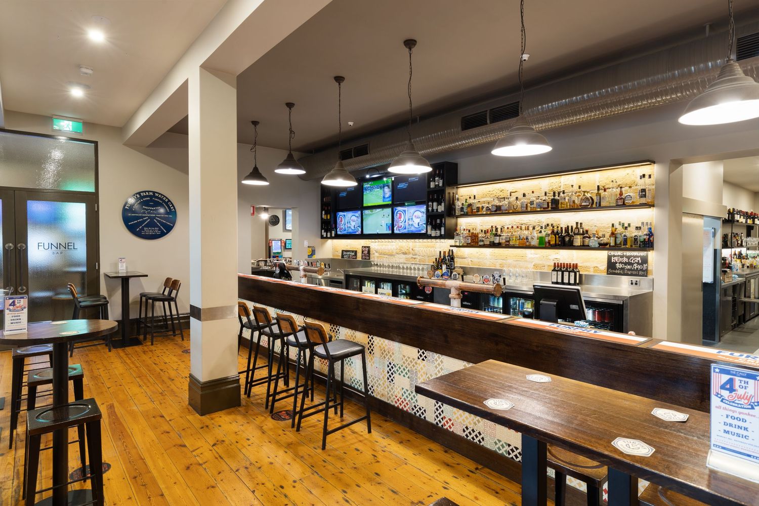 Interior photograph of a pub or bar fit-out with timber bar and television screens.