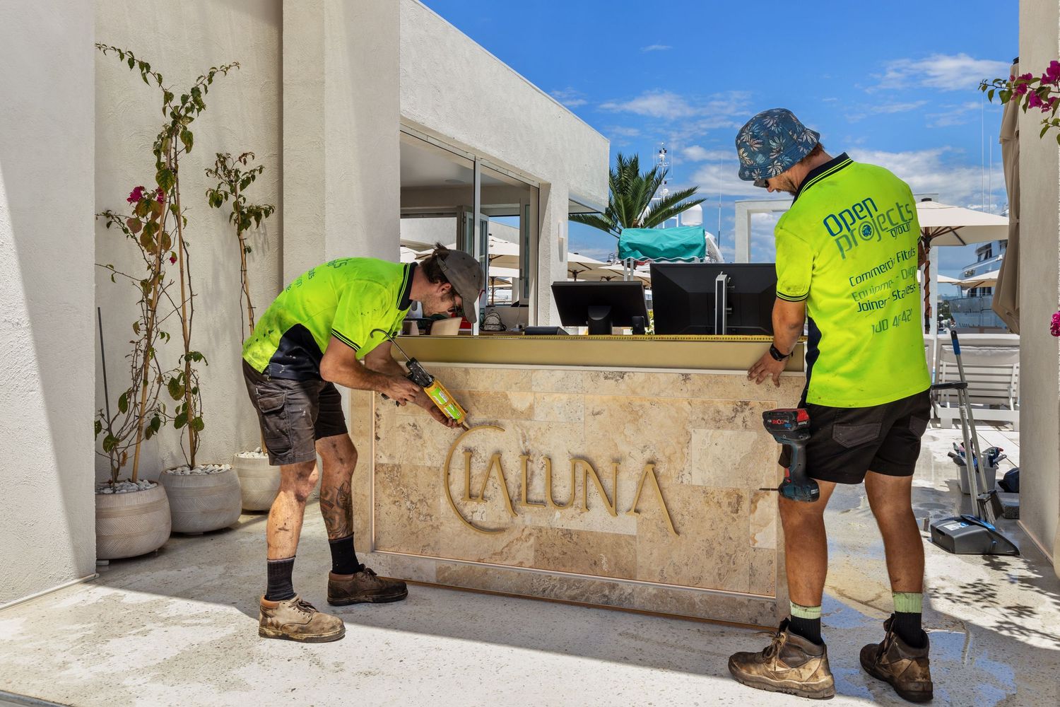 Tradespeople installing signage on a commercial building during construction.