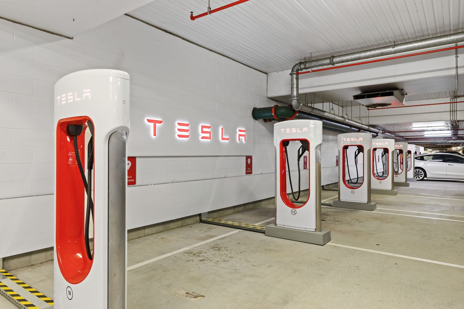 Photograph of a Tesla electric vehicle charging area in a parking garage.