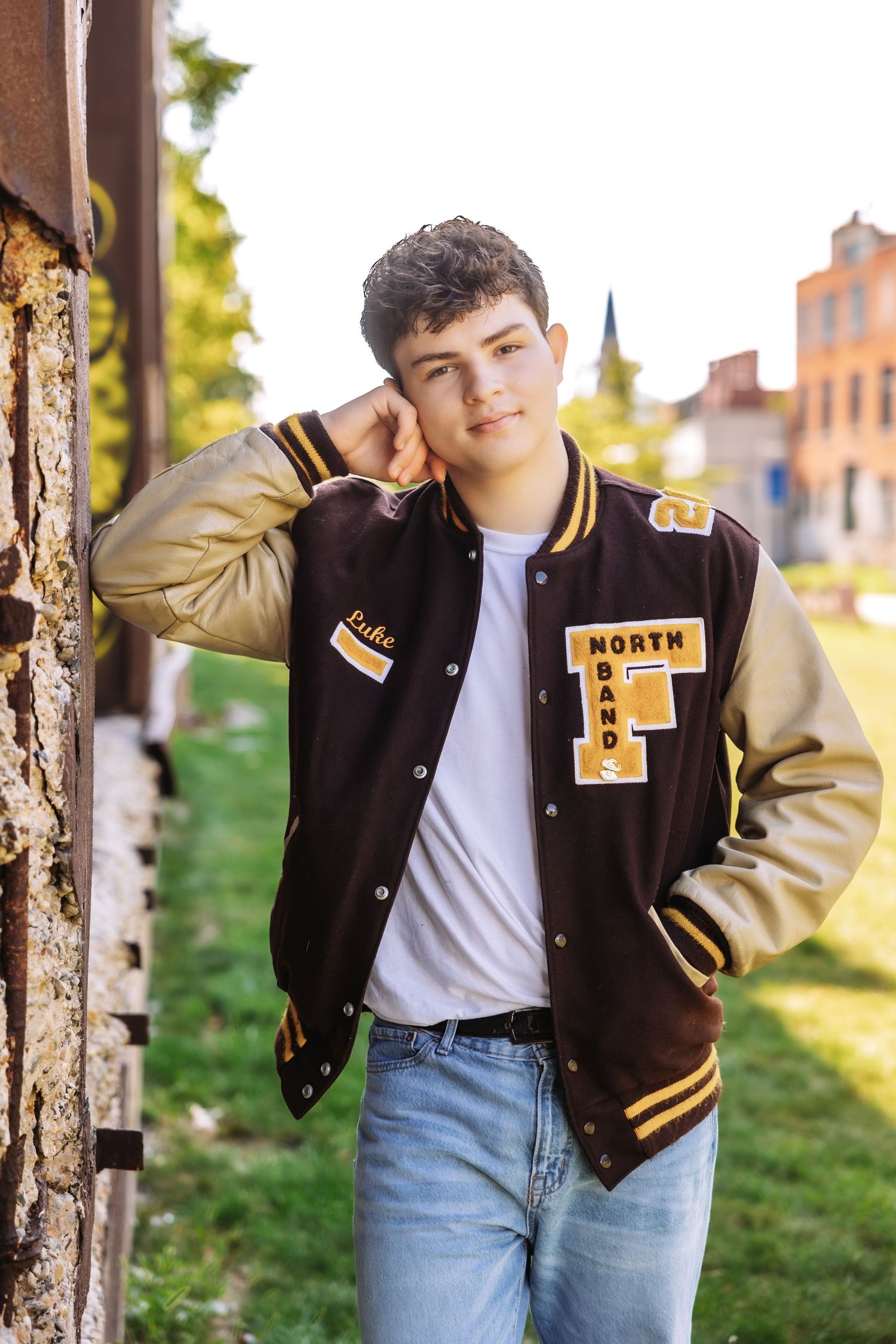 Senior boy poses in varsity jacket on the Dequindre Cut by Rachel Martinez Photography, Michigan photographer