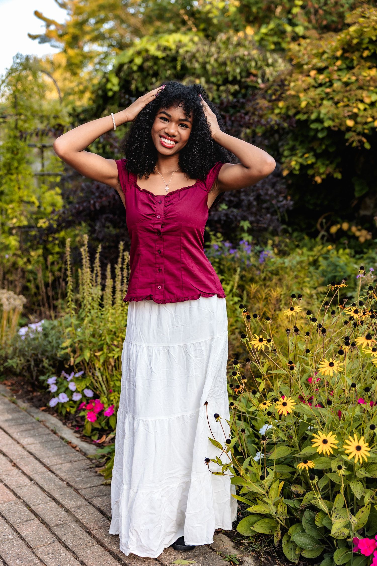 Senior girl poses in garden at Cranbrook House and Gardens by senior photographer Rachel Martinez in Metro Detroit