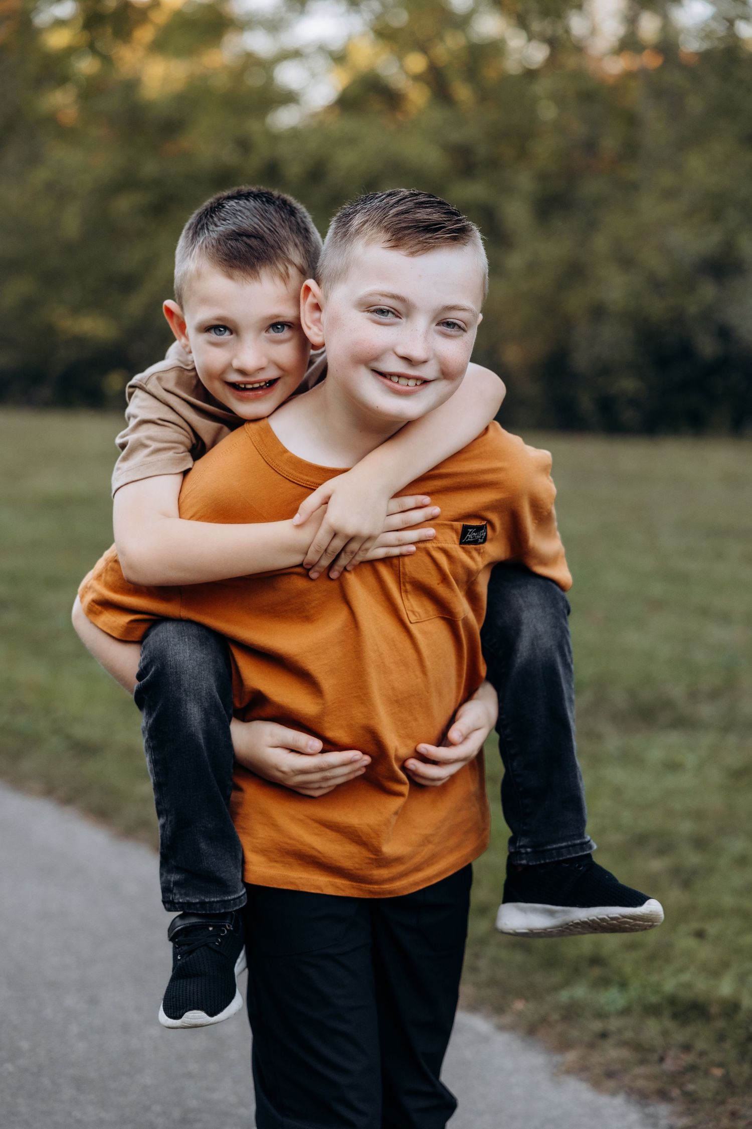 Big brother gives little brother a piggy back ride in Northville Michigan by Rachel Martinez Photography, Michigan photographer
