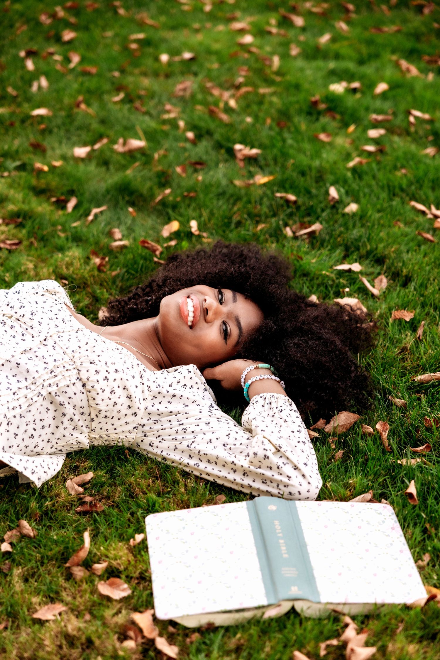 Senior girl lays in the grass with a book at Cranbrook House and Gardens by senior photographer Rachel Martinez in Metro Detroit