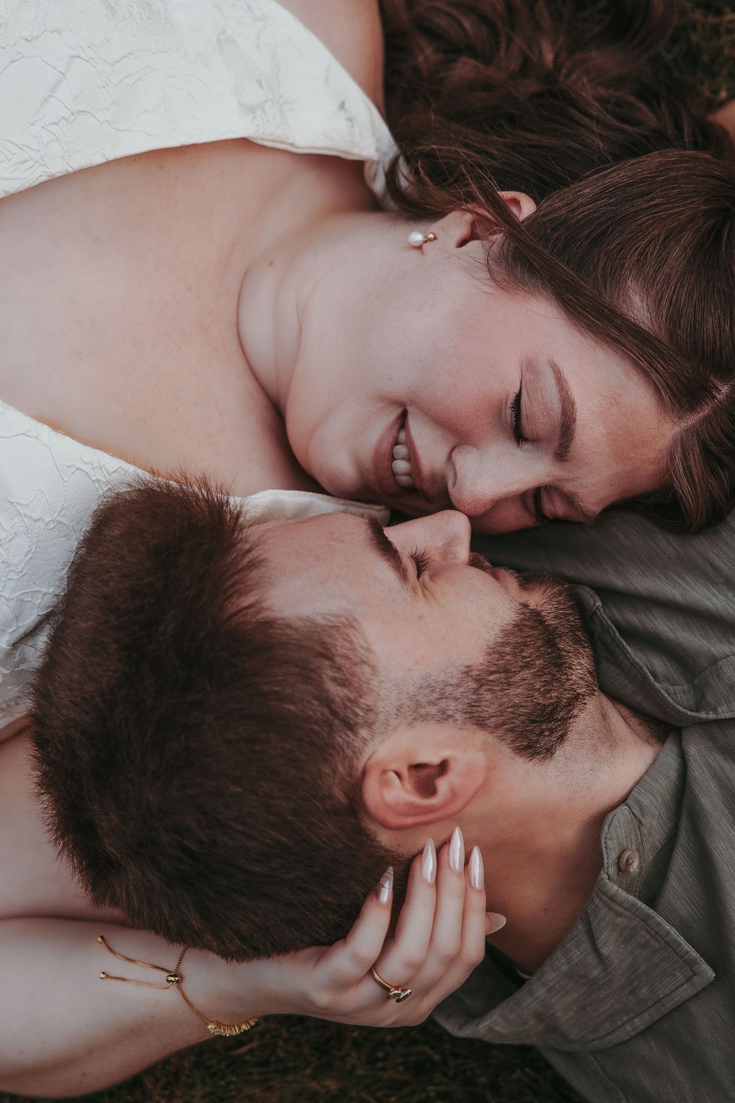 Couple lays in the grass and touch noses Couple snuggles at Greenmead Livonia by Rachel Martinez Photography, Michigan Wedding Photographer