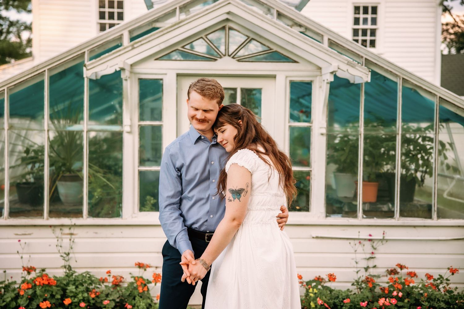 Couple snuggles in front of a greenhouse at Greenmead Livonia by Rachel Martinez Photography, Michigan Wedding Photographer