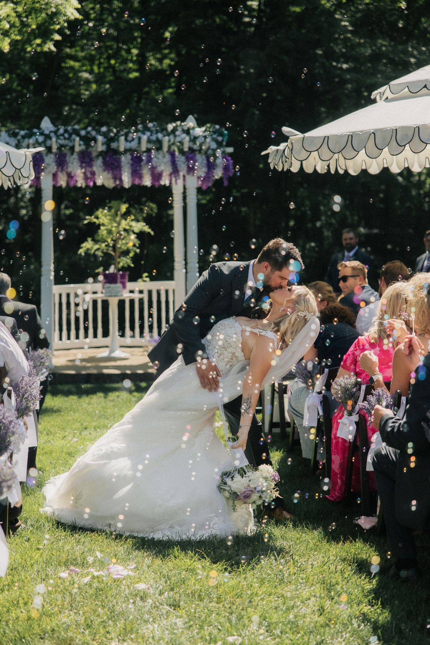 Couple dips for a kiss with bubbles blowing around them at Hidden Grove Estate by MI wedding photographer Rachel Martinez