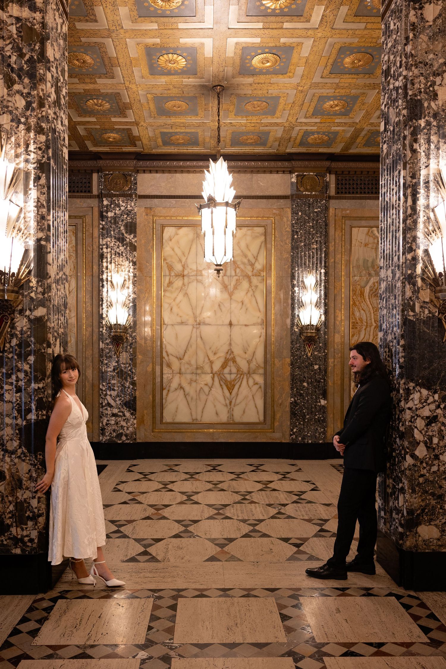 Engagement session at the Fisher Building in Downtown Detroit-vCouple poses against pillars surrounded by light. Rachel Martinez Photography