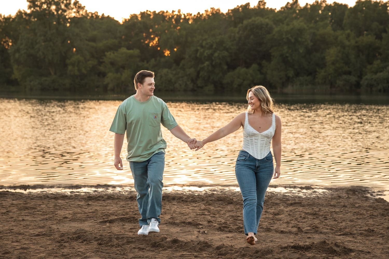 Couple holds hands and walks in the sand at Island Lake State Park in Brighton Michigan by Rachel Martinez Photography