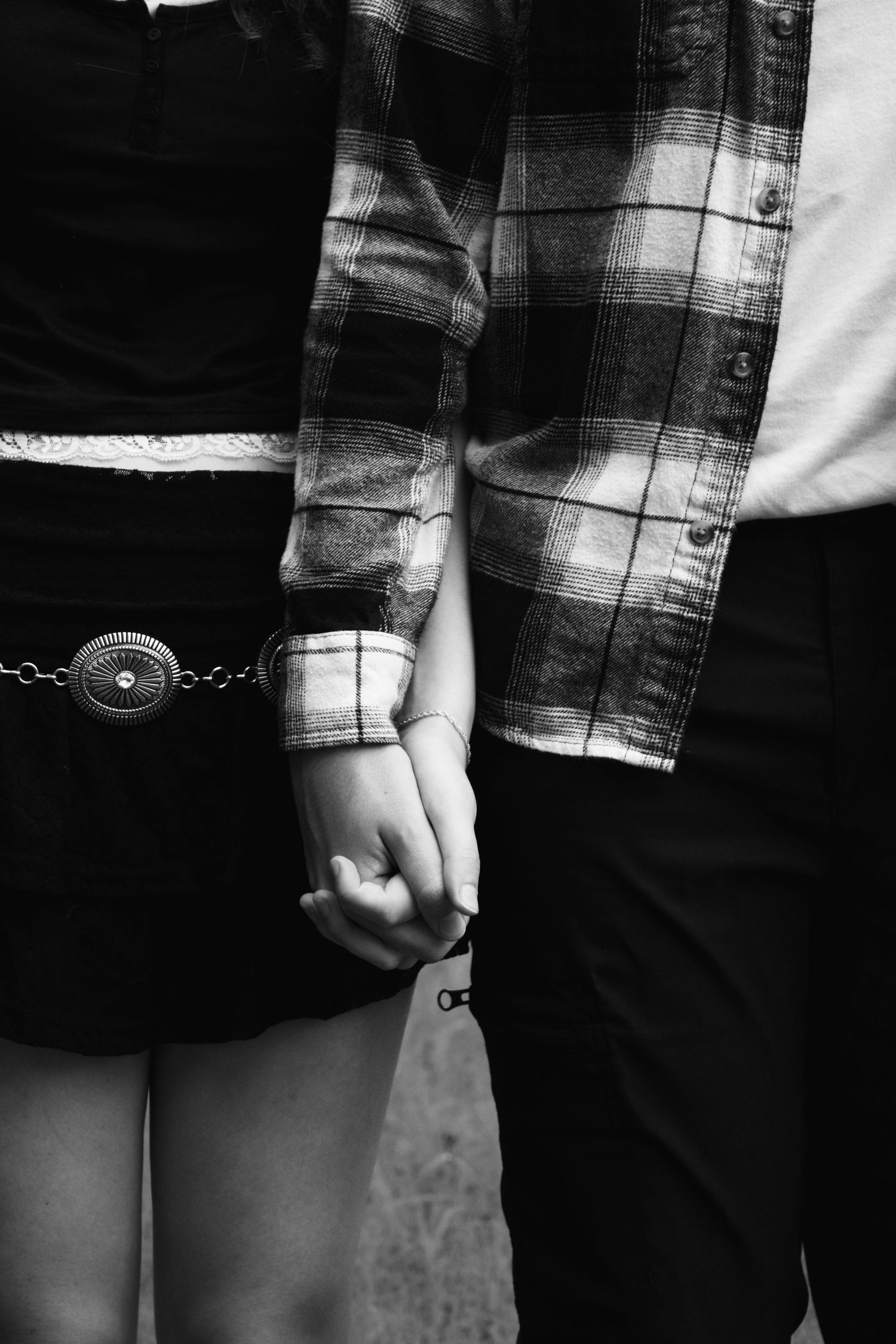 Black and white close-up of couple holding hands, one wearing a plaid flannel shirt.