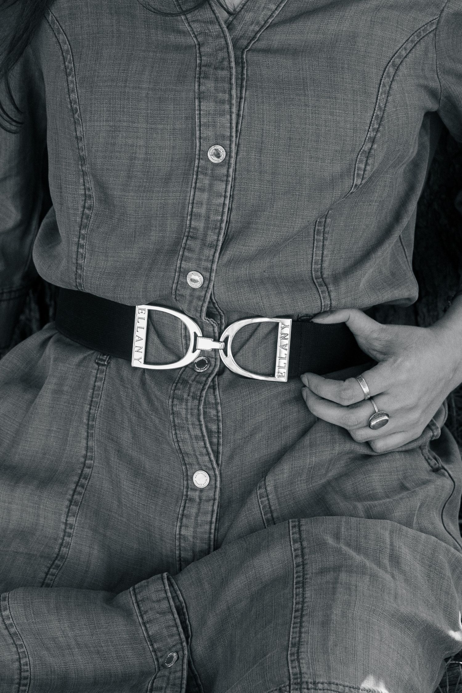 Black and white close-up of woman in denim dress with decorative silver belt buckle.