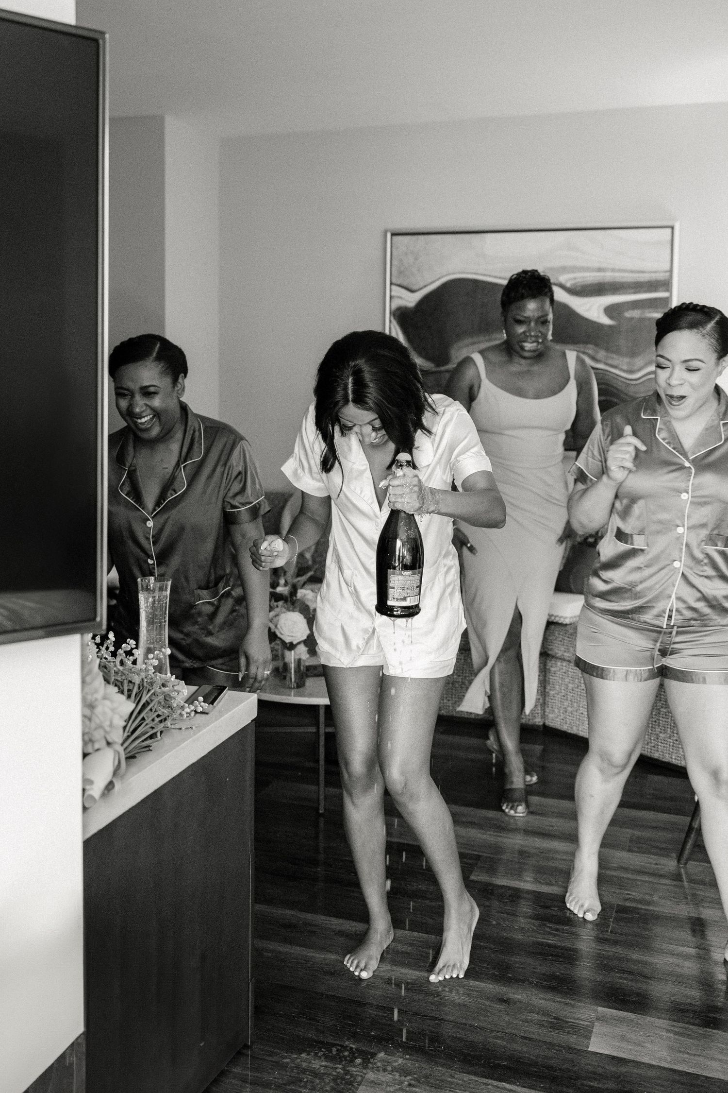 Bride getting ready in her bridal pajamas popping champagne with her bridal party captured by Lakeland wedding photograp