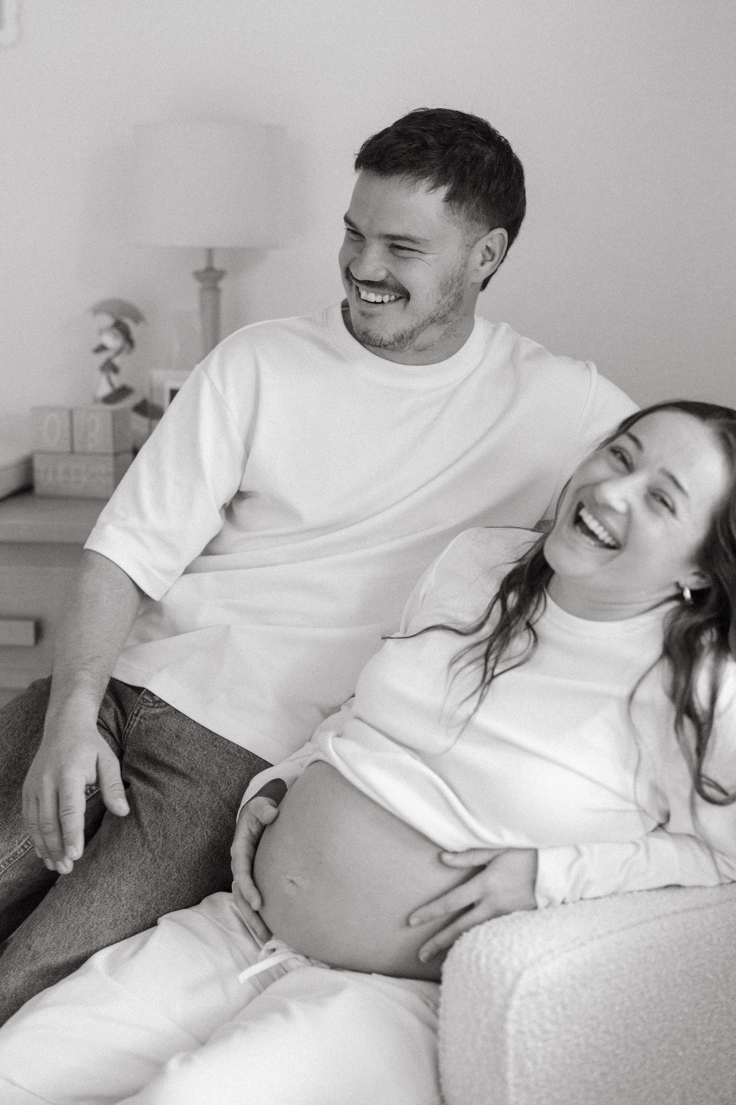 Pregnant woman sitting beside her partner in their nursery