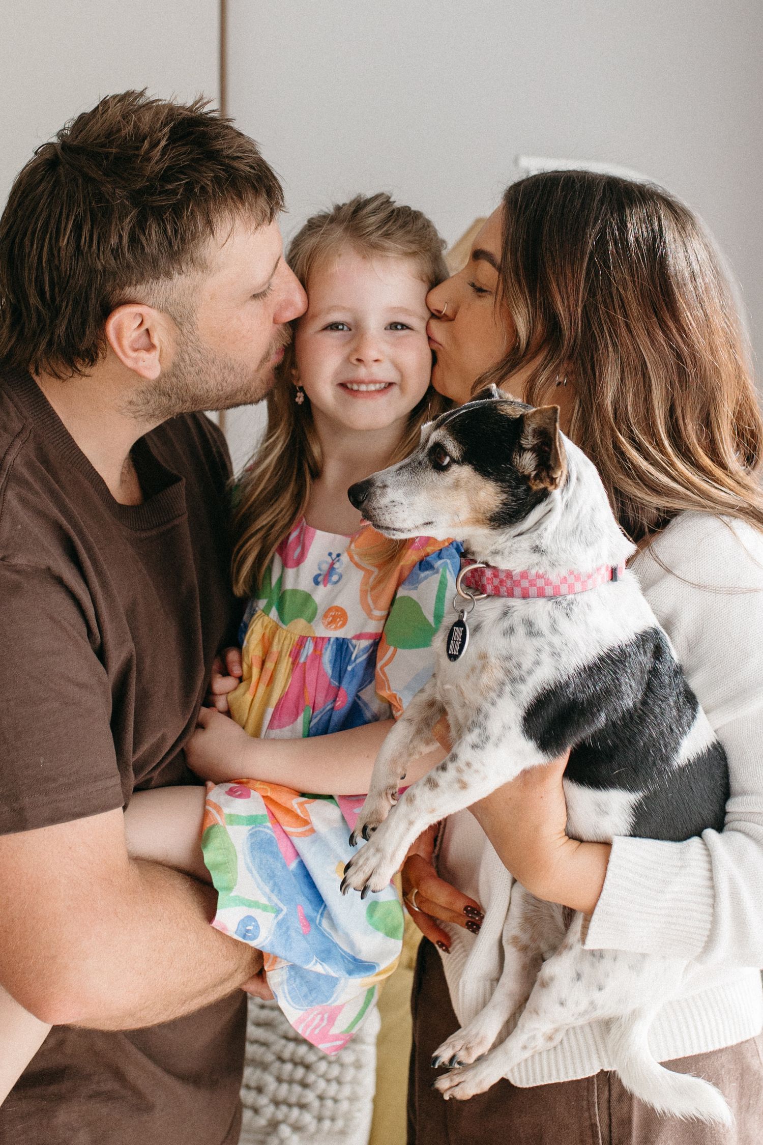 Mother and father kissing daughter