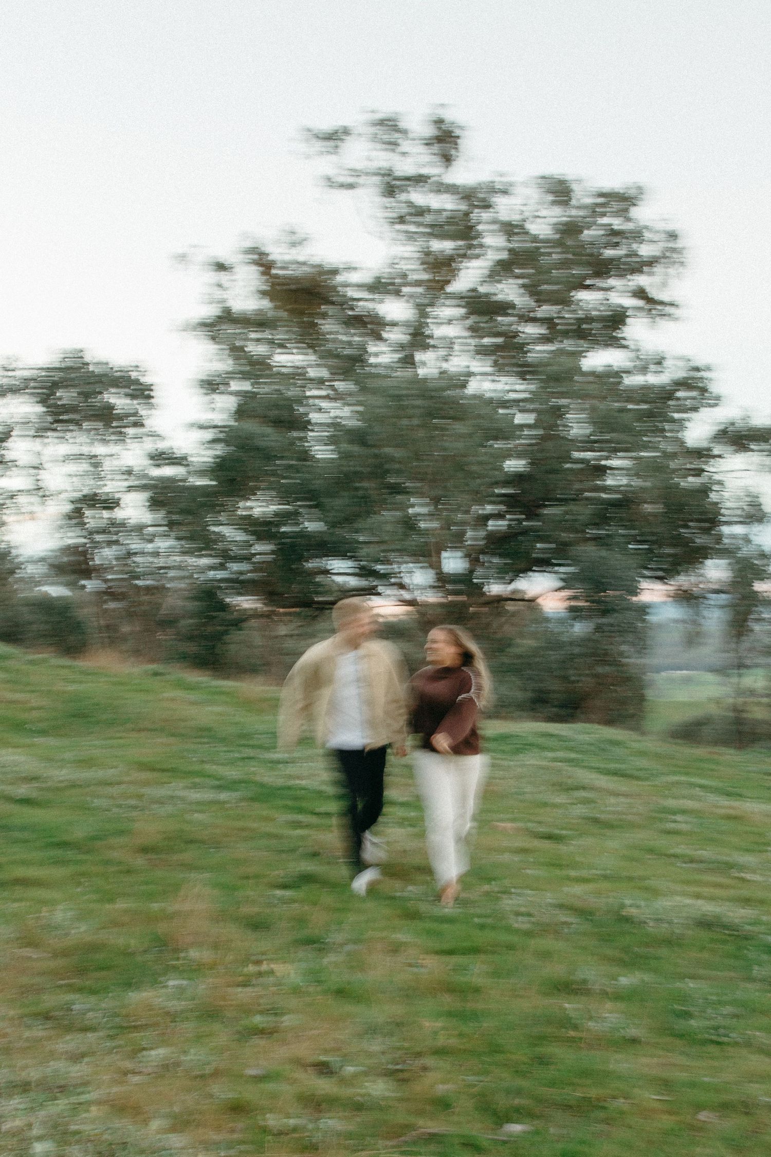 couple running through field at sunset