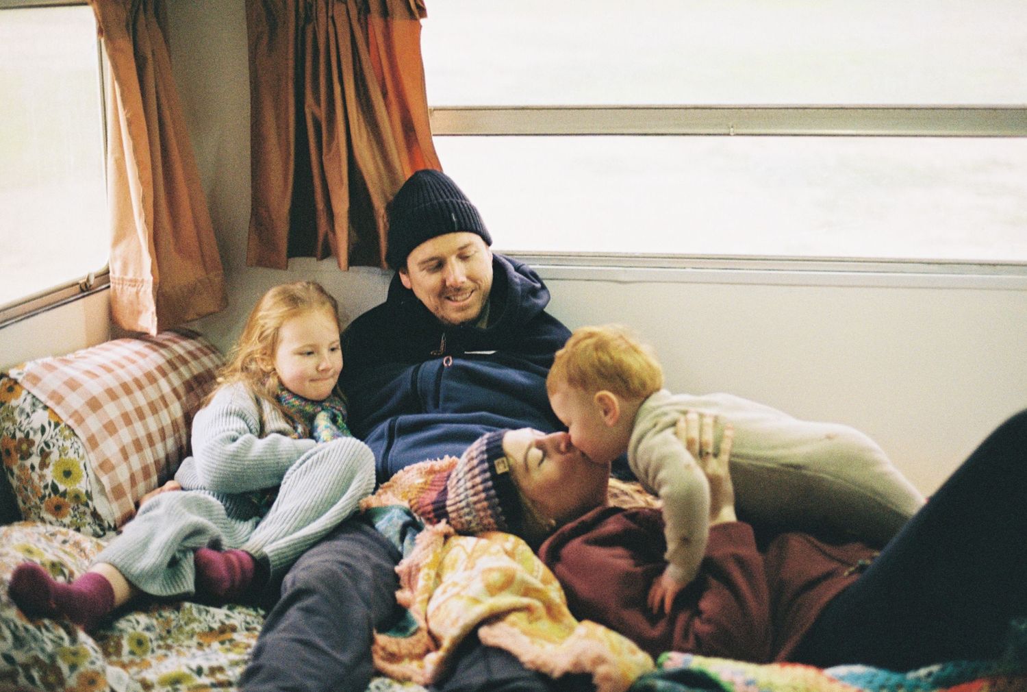 family cuddling inside caravan captured on 35mm film