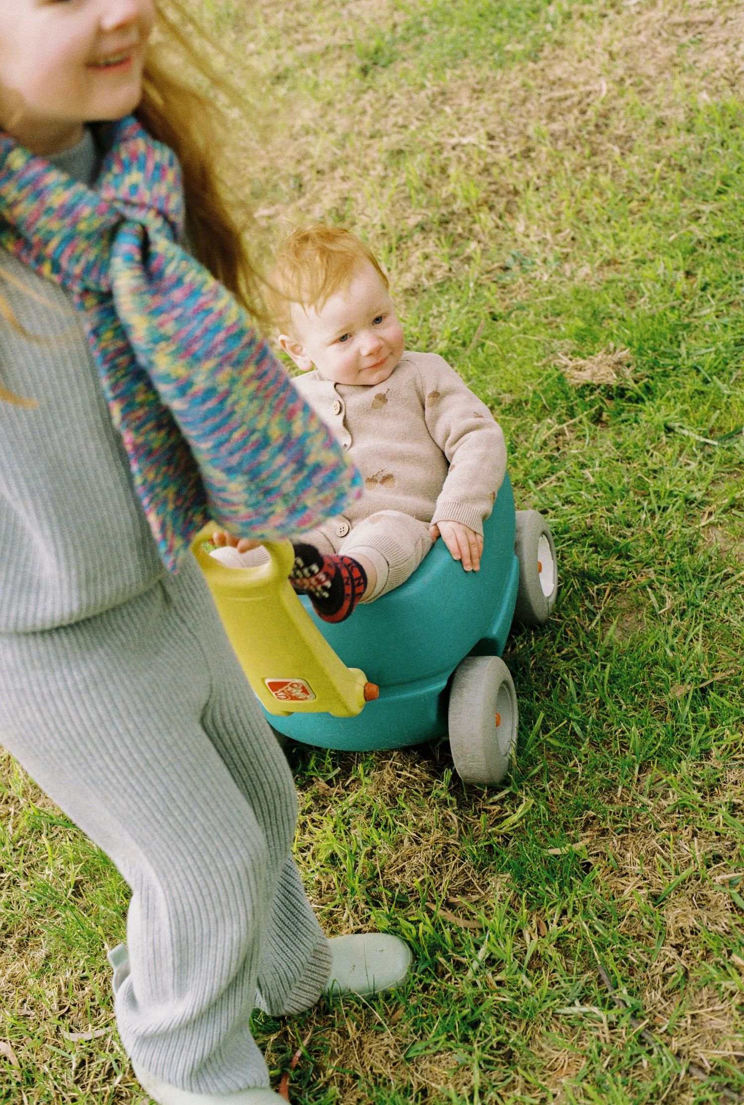 girl pulling her brother in toy cart captured on 35mm film
