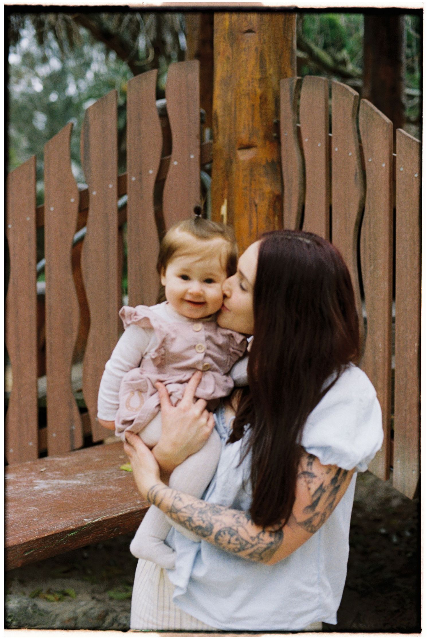 mother snuggling into baby daughter outside captured on 35mm film