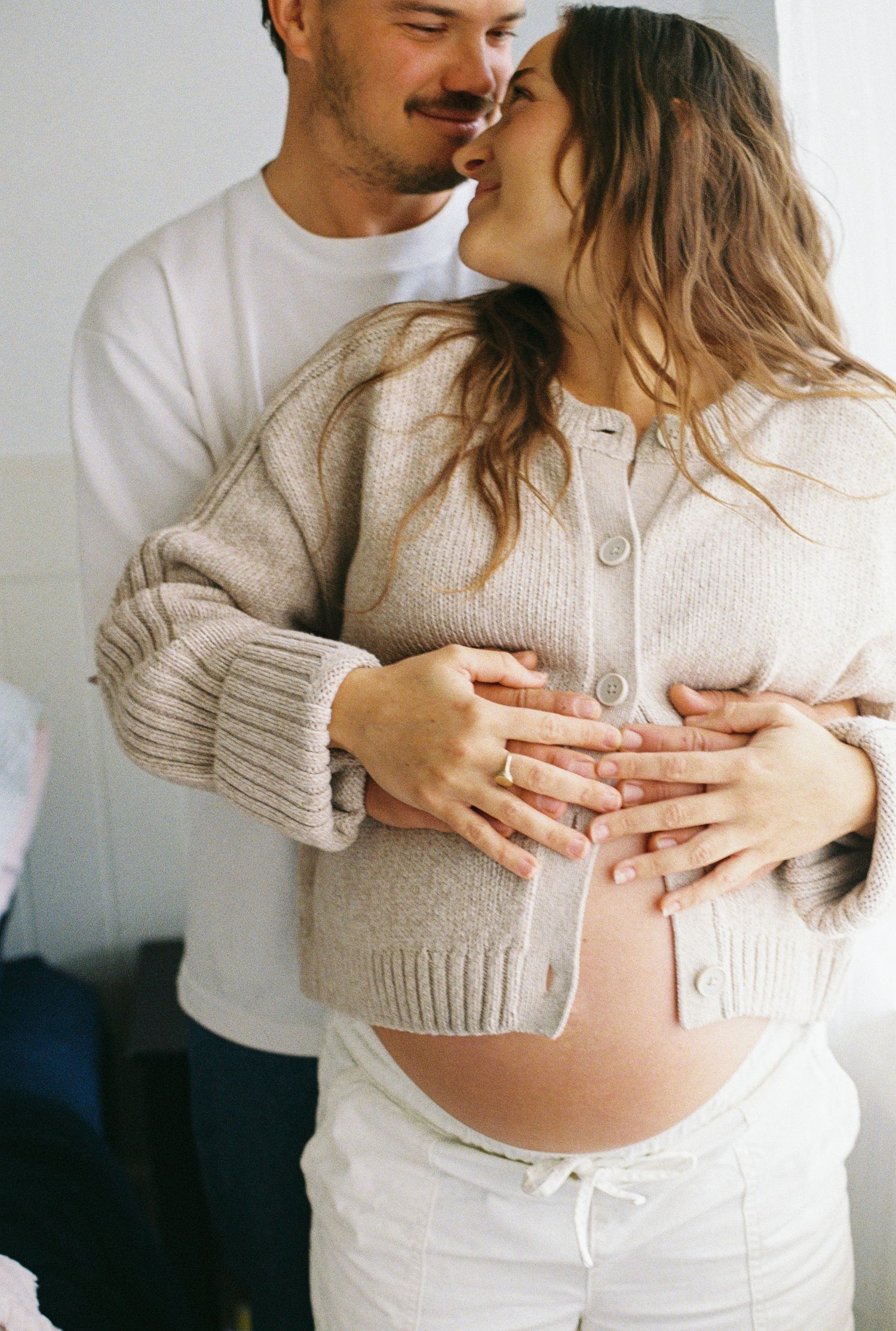 Pregnant woman standing beside her partner in their nursery
