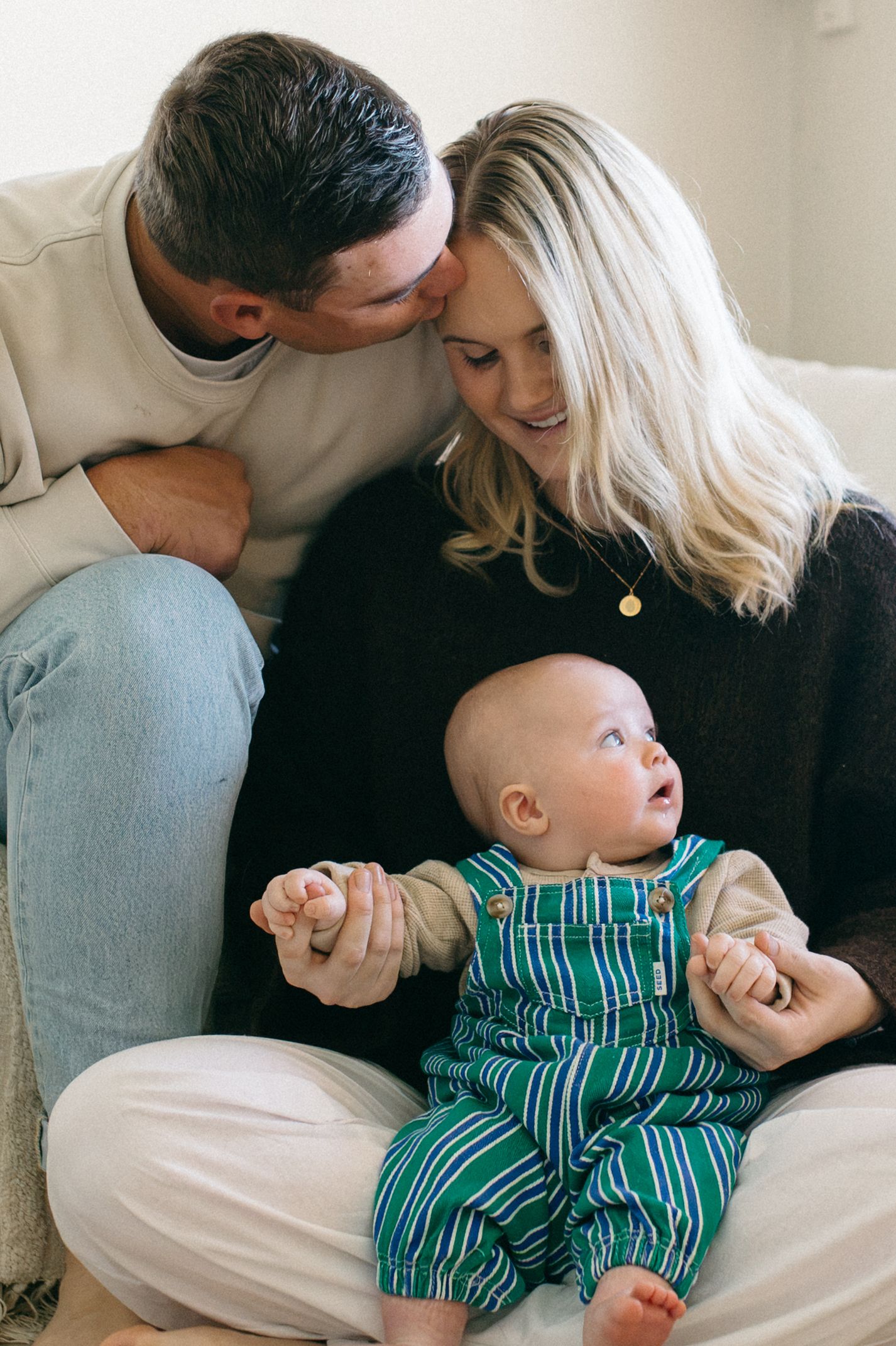 dad kissing mum while she plays with their baby inside