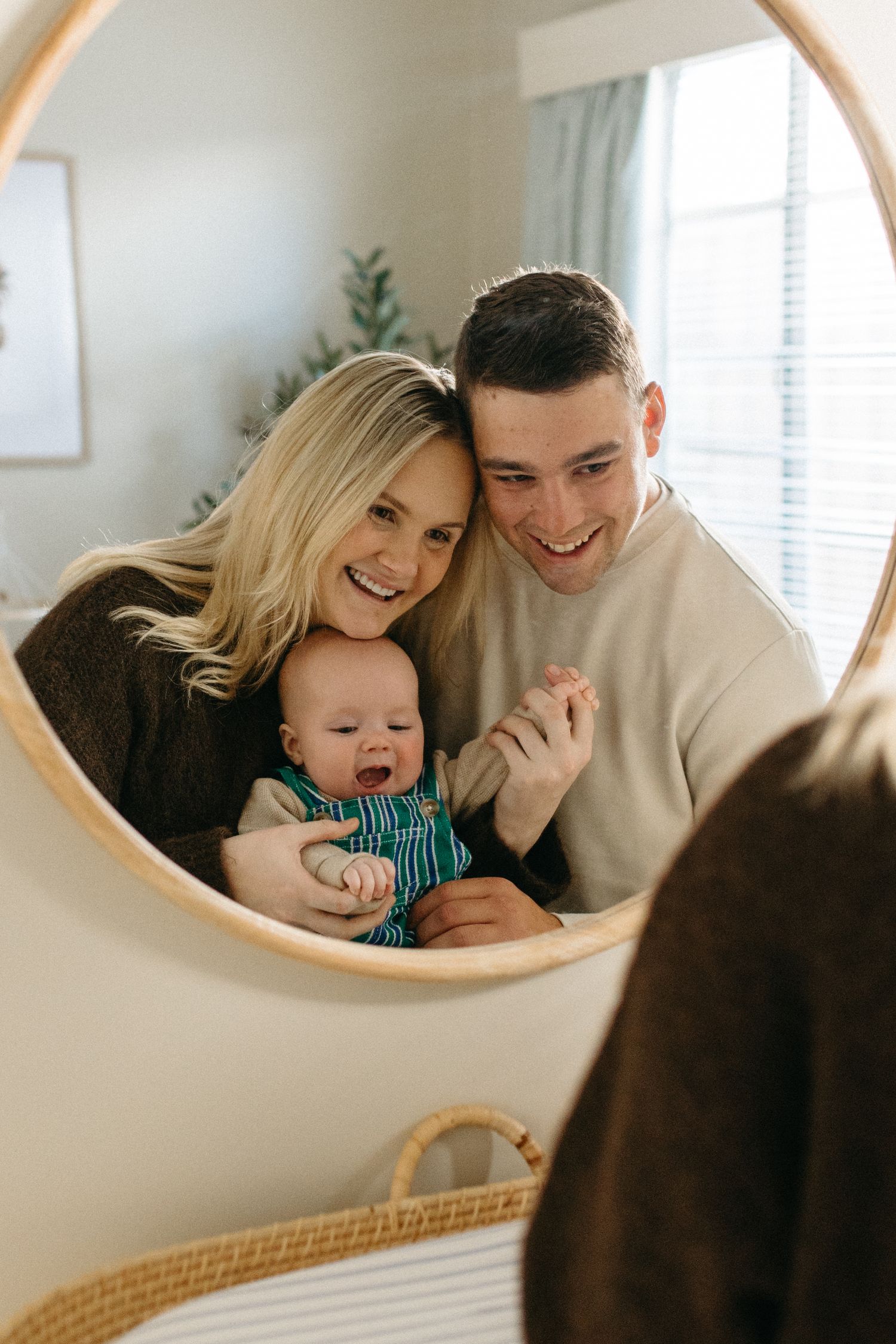 family smiling into a mirro in baby nursery