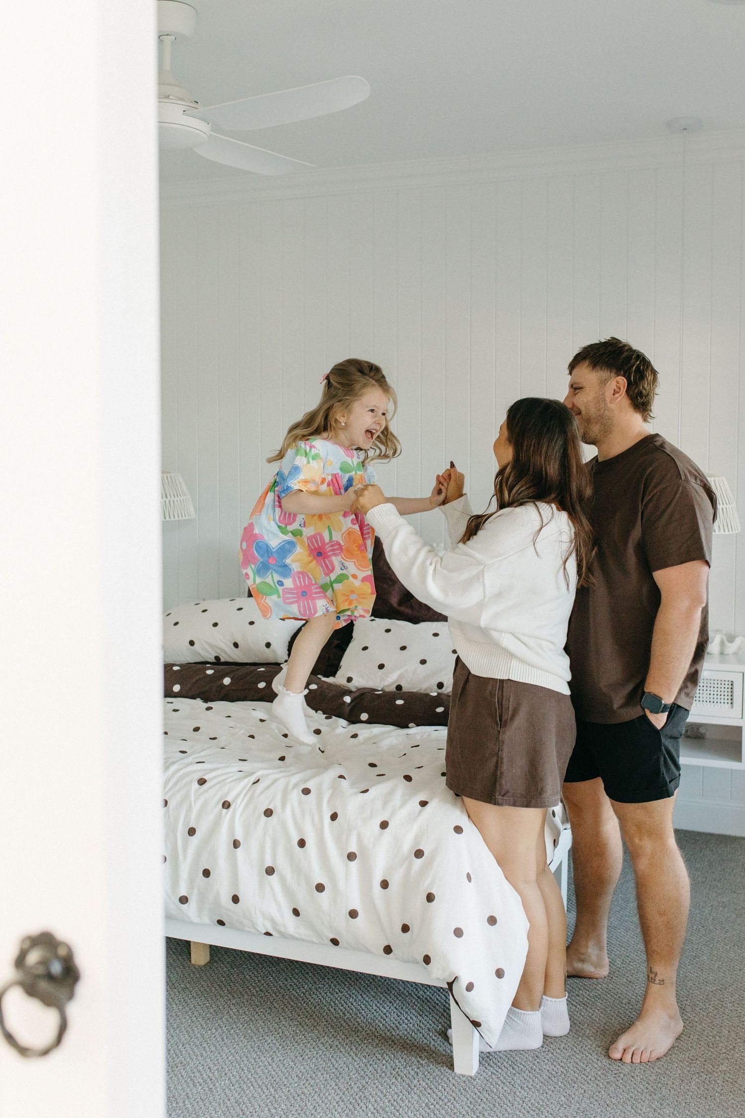 daughter jumping on bed while mum and dad watch