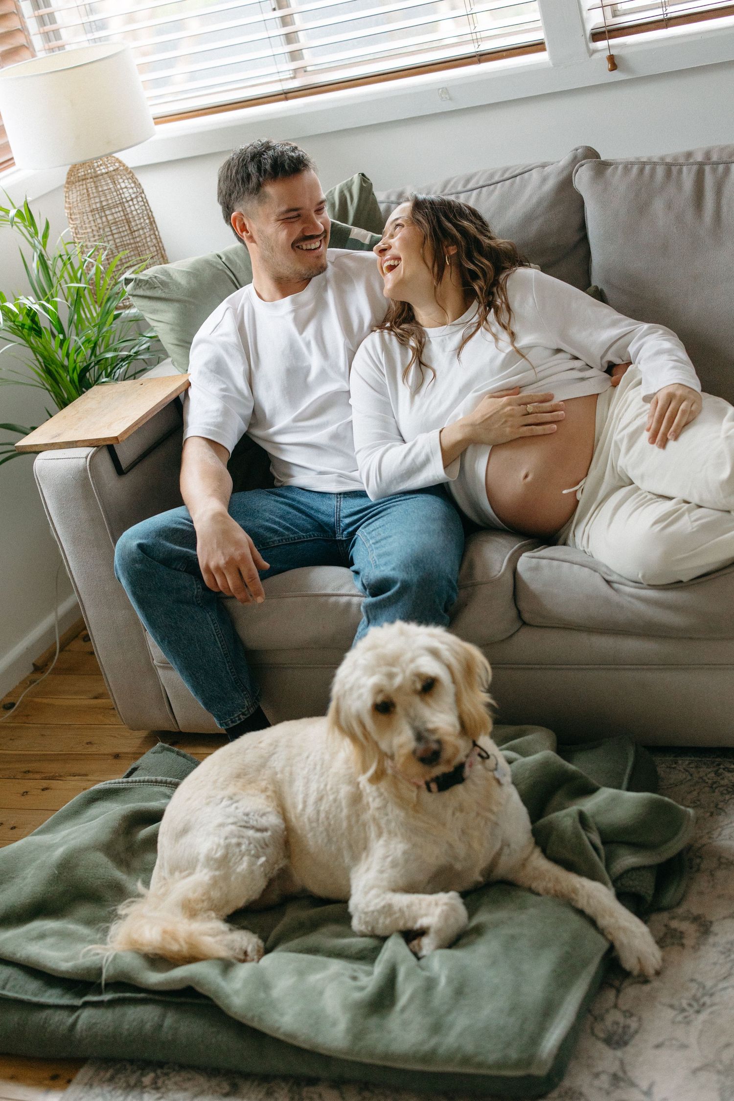 Pregnant woman sitting beside her partner and dog in their living room