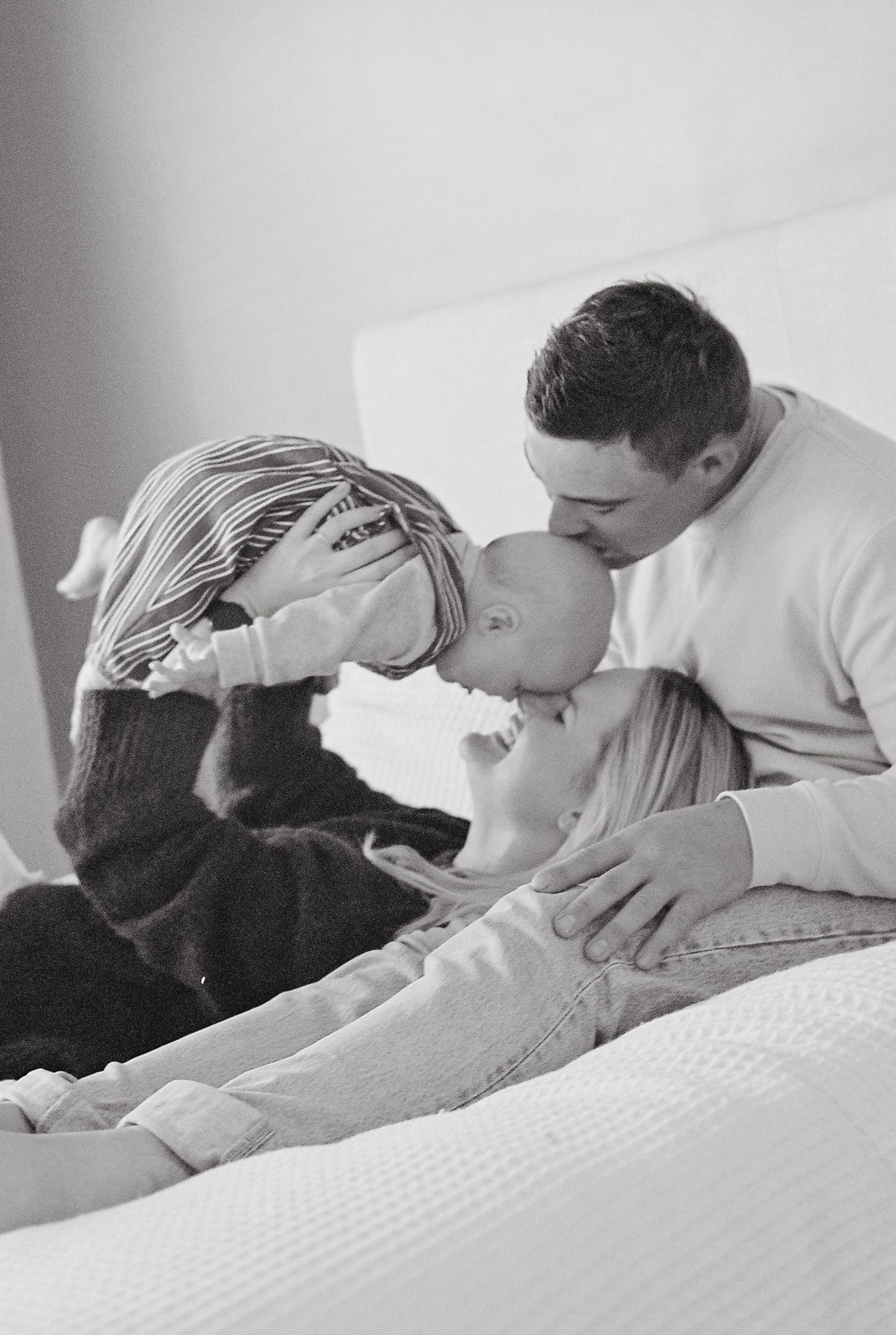 mum and dad laying on their bed lifting their babu in the air captured on 35mm film