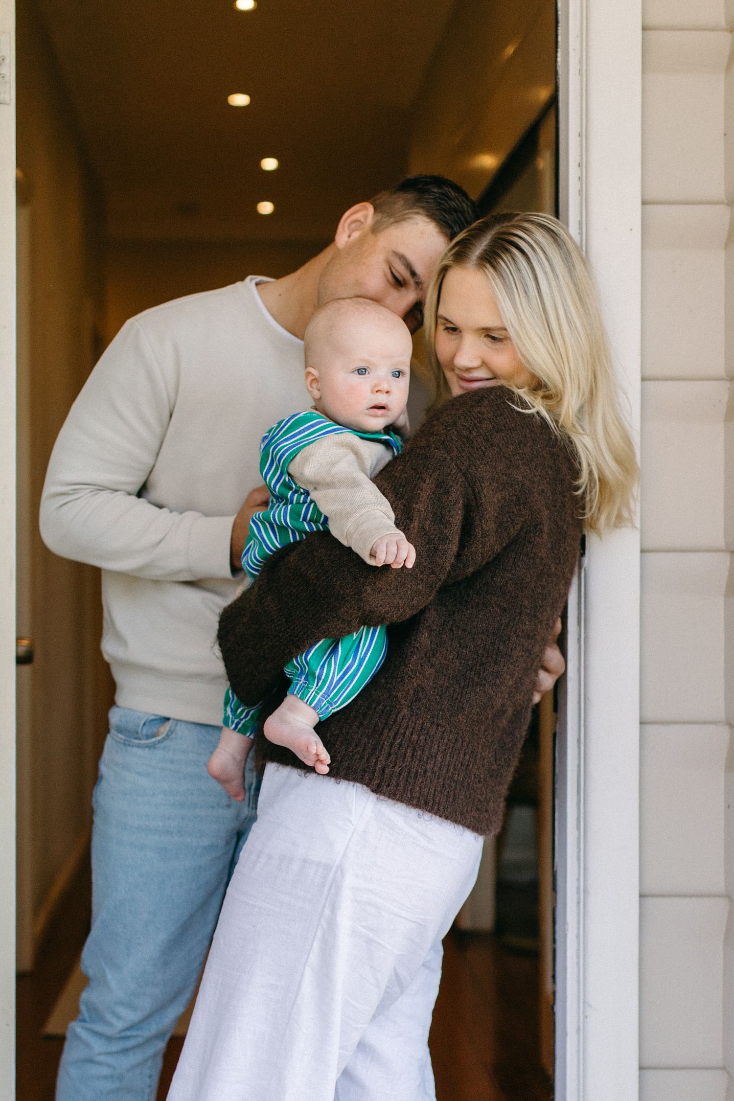 family snuggling in the doorway entrance of their home