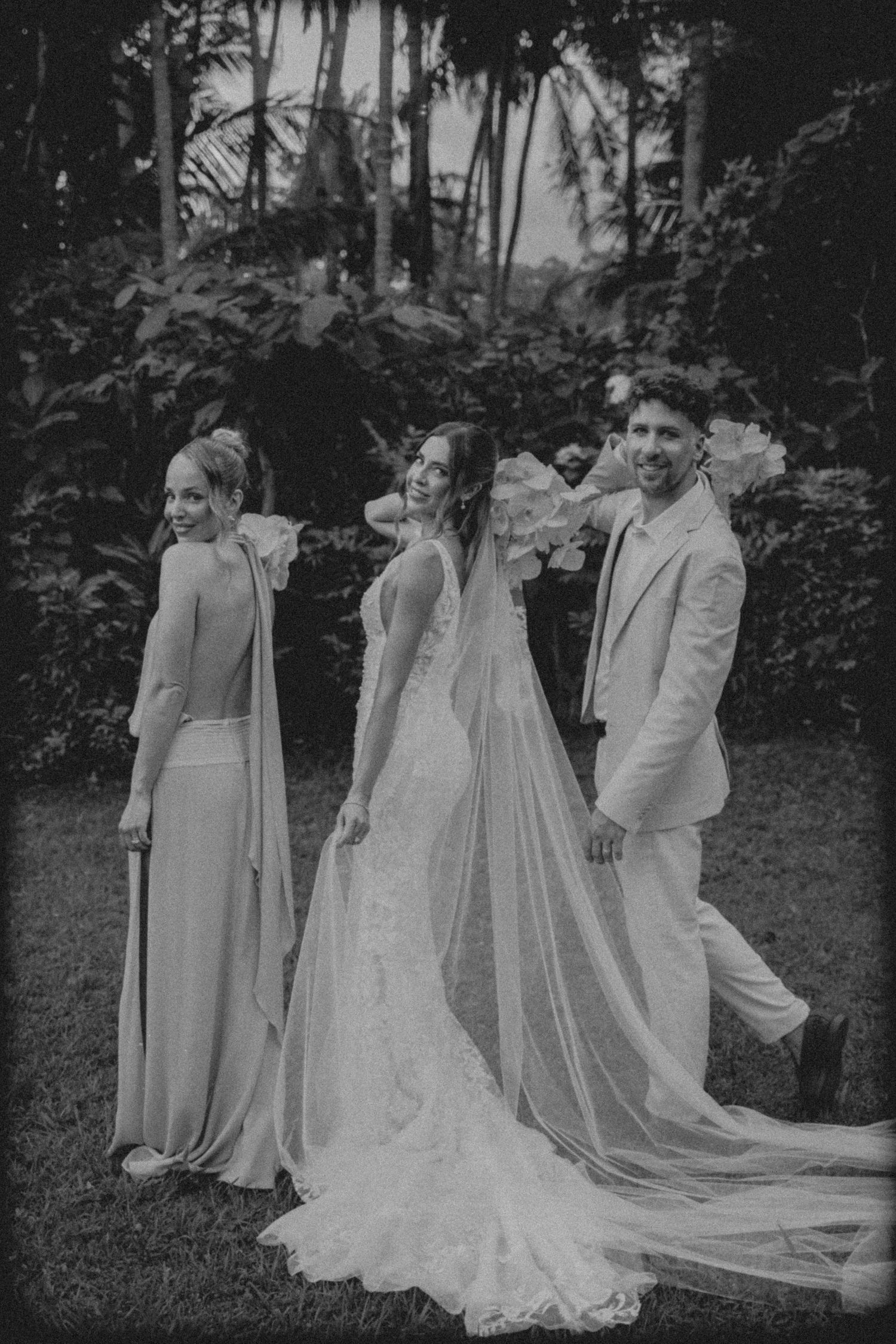 A black and white wedding party photo series showing a group in formal attire posing together outdoors.