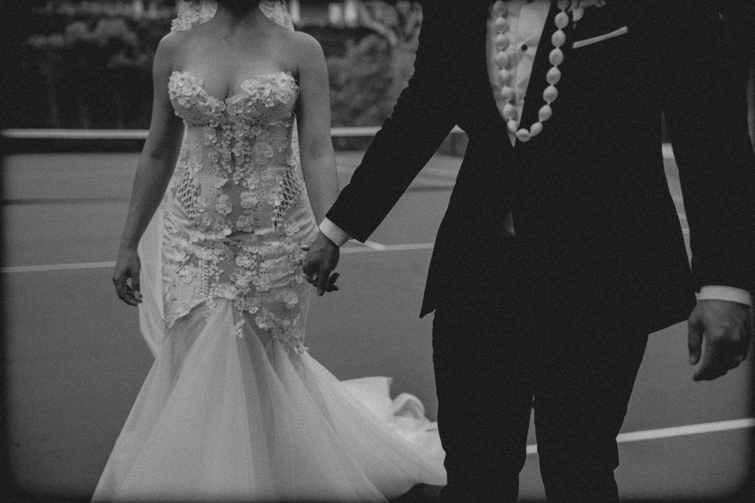 Black and white wedding photograph showing a couple walking together in formal attire with a flowing bridal gown.