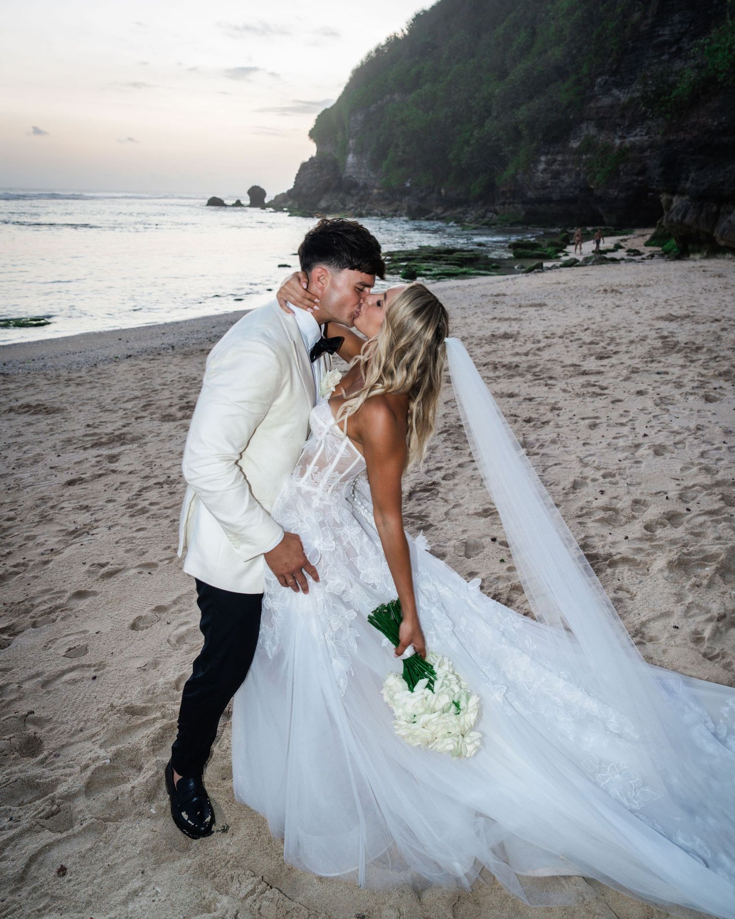 A romantic beach wedding photo session at sunset with a couple sharing intimate moments on a sandy shore.