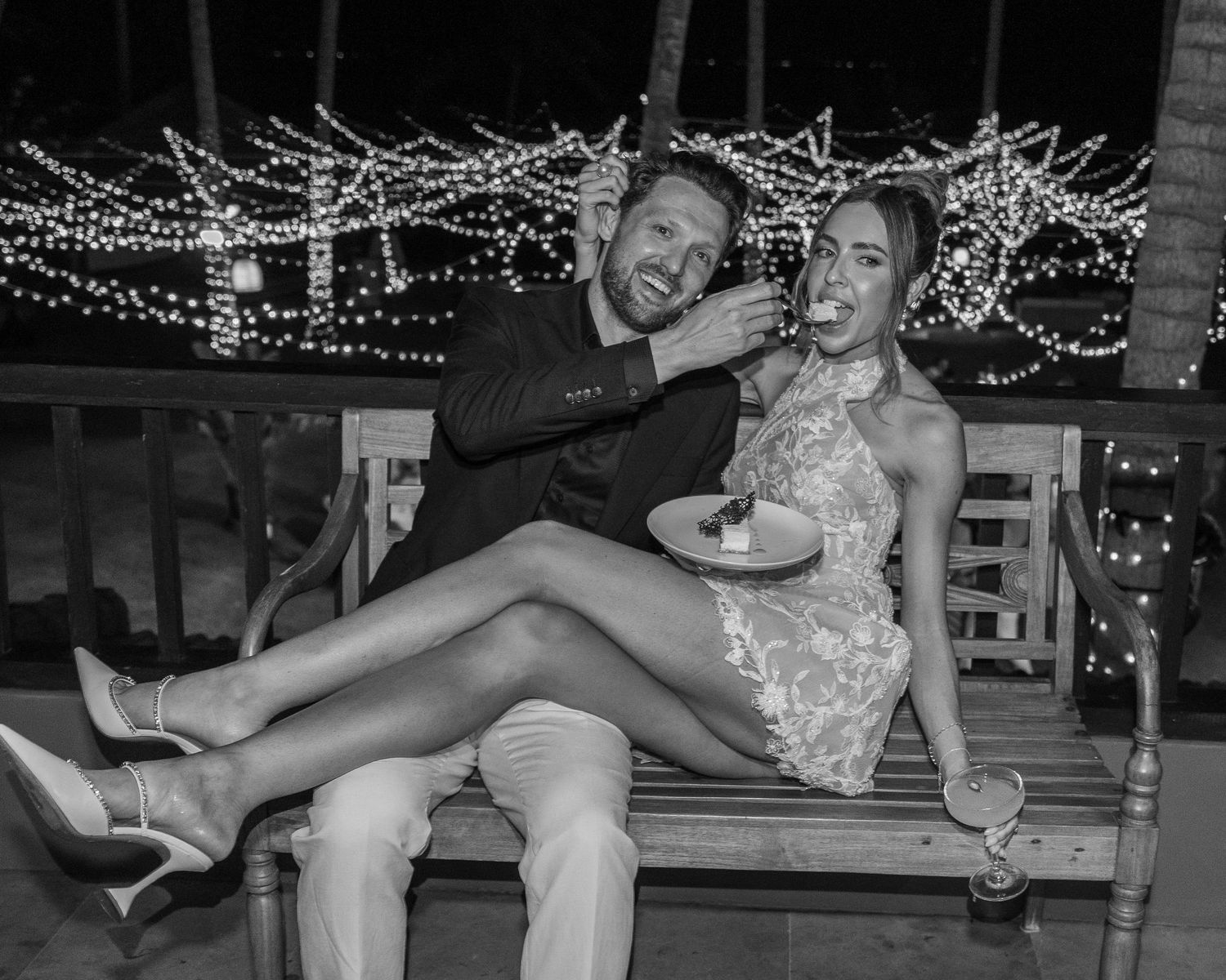 A black and white photo sequence of a couple sharing intimate moments under string lights at night.