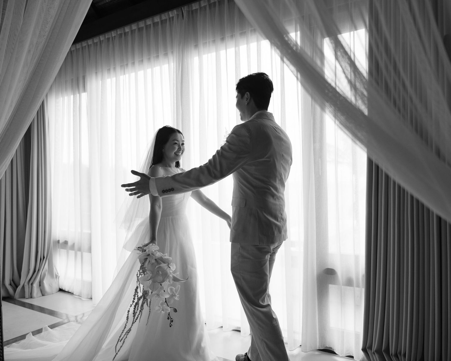 A black and white wedding photoshoot sequence showing intimate moments between a couple near curtained windows.