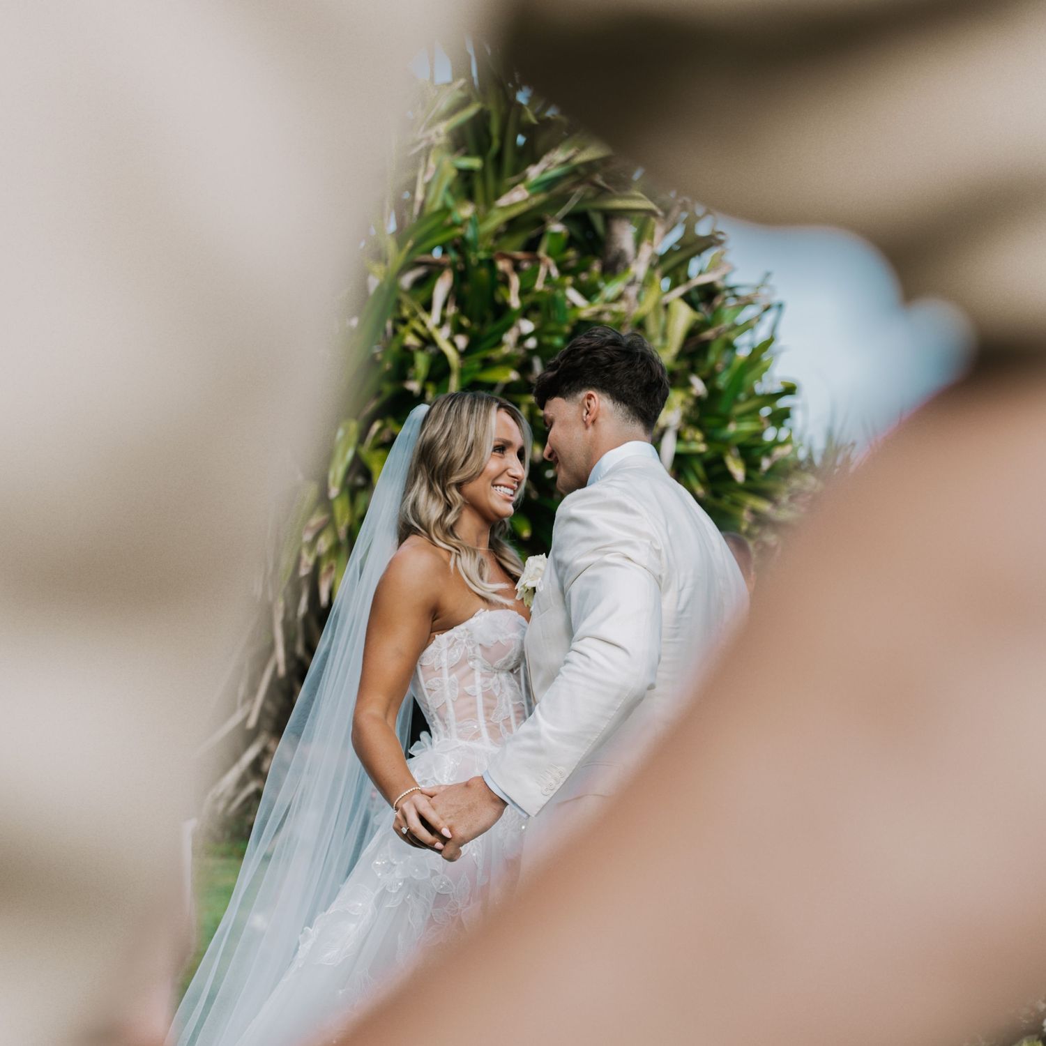 A romantic wedding couple shares an intimate moment in a garden setting during their wedding celebration.