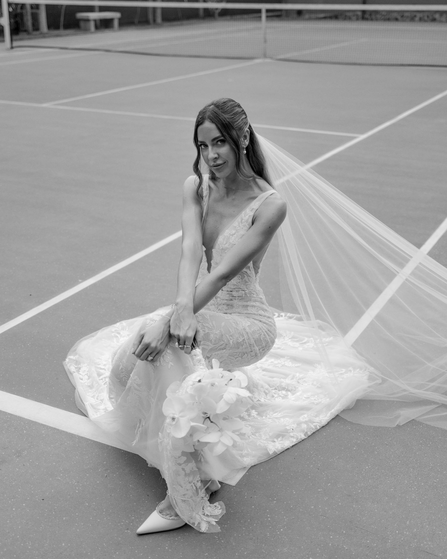 A series of black and white photos showing a bride in a lace dress posing on a tennis court.