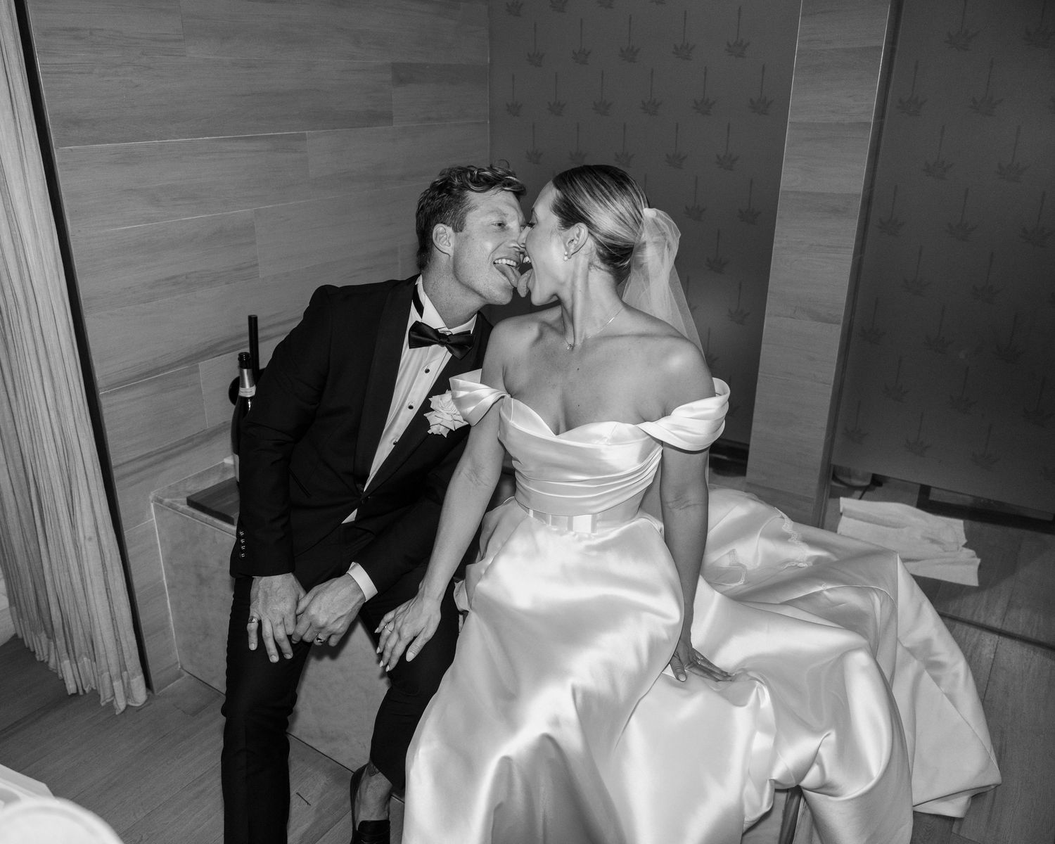 A romantic black and white photo of a couple in formal wedding attire sharing an intimate moment.