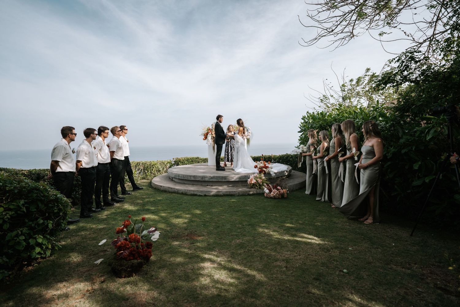 Wedding ceremony setup on coastal cliff with wedding party lined up on both sides.