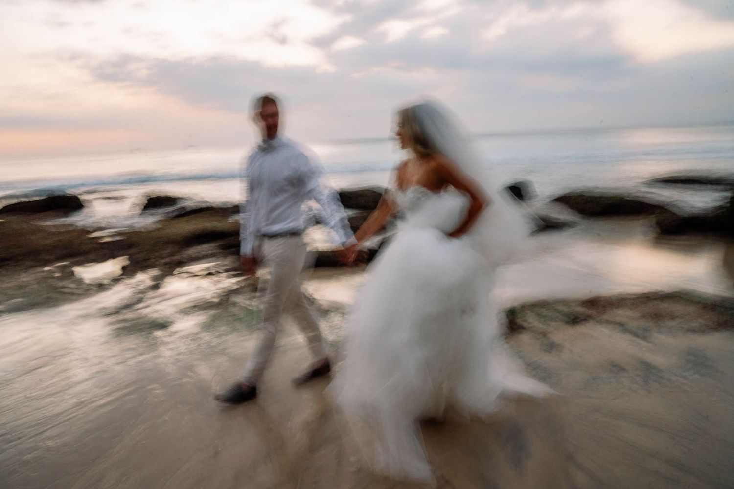 Motion blur sequence of couple walking along beach at sunset creating dreamy romantic atmosphere.