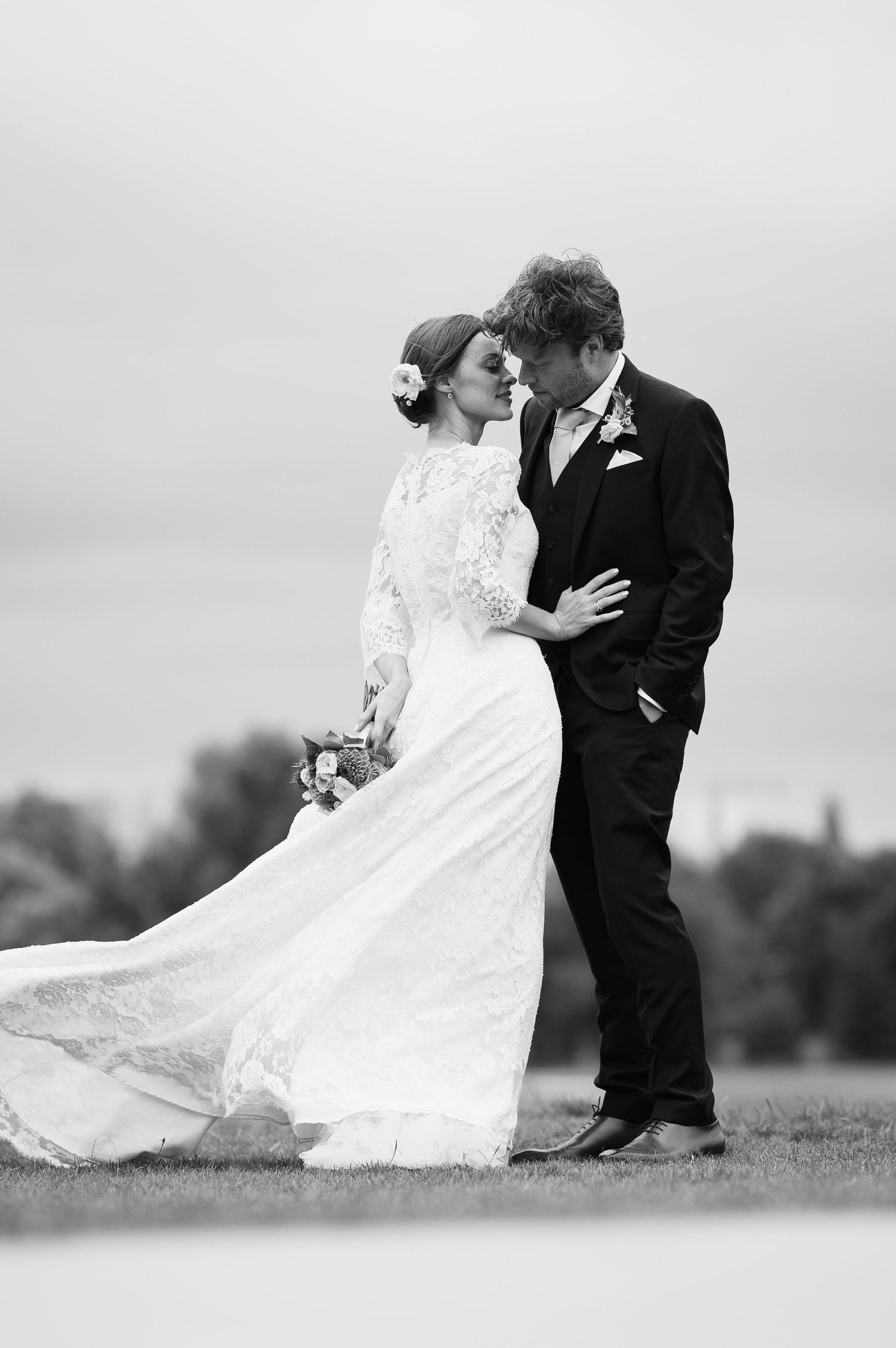 Black and white photo of a bride and groom sharing a romantic moment outdoors on their wedding day.