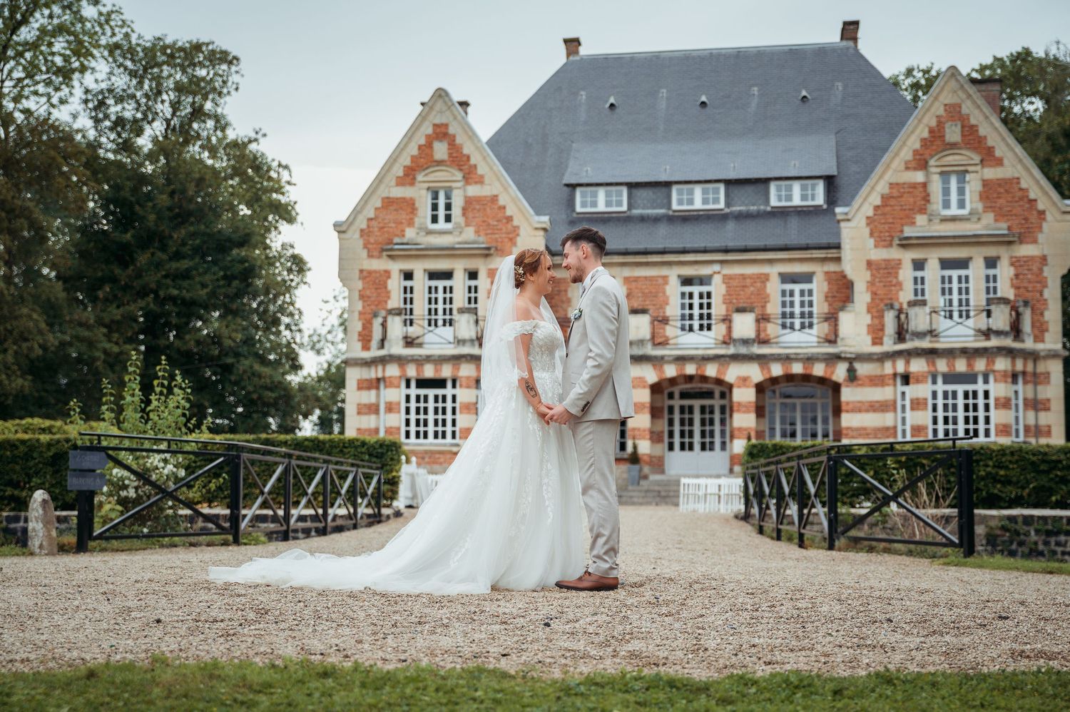 Wedding couple sharing romantic moment in front of elegant French brick chateau venue.