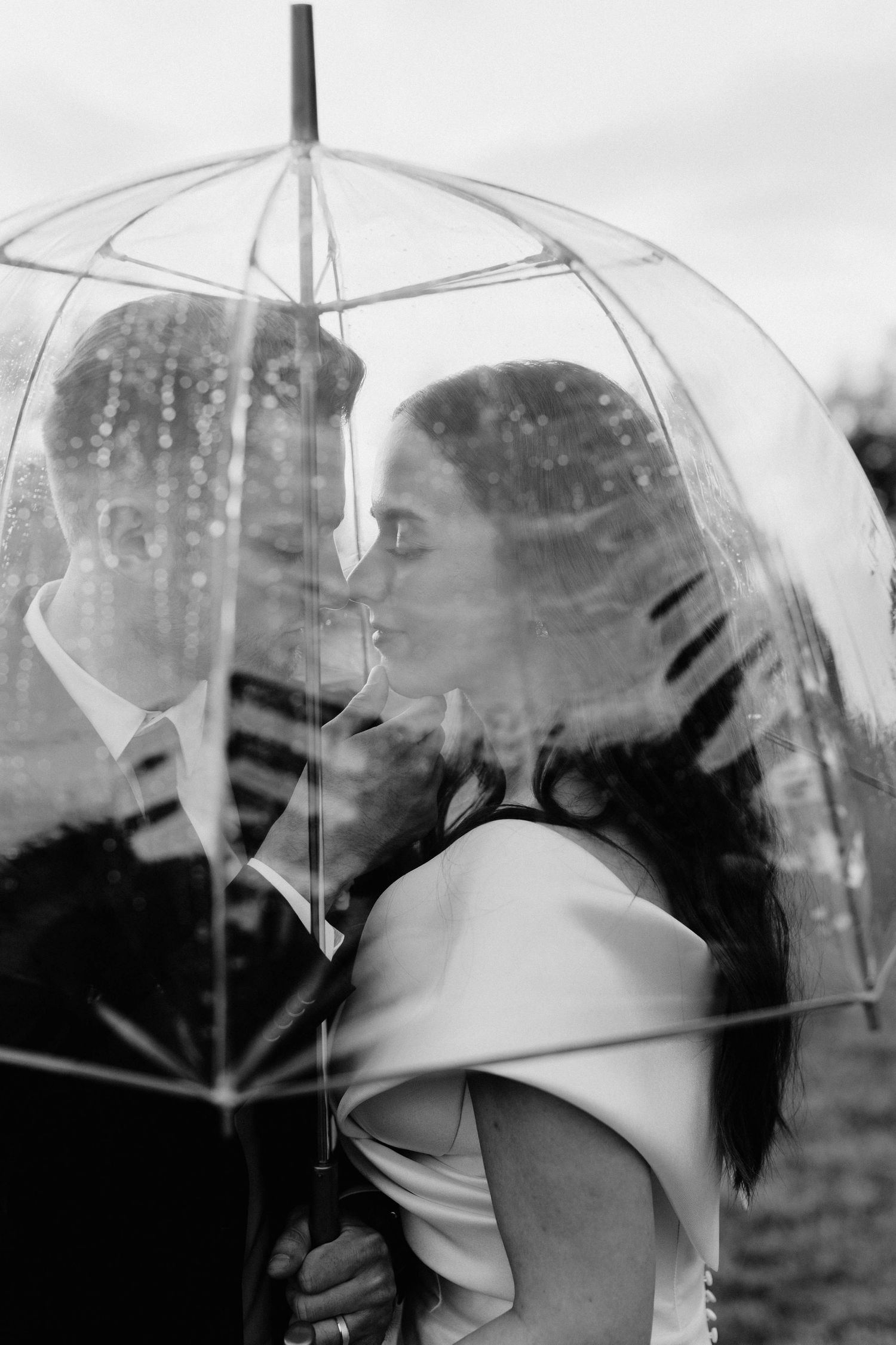 Clear umbrellas creating artistic reflections and patterns in black and white photography.
