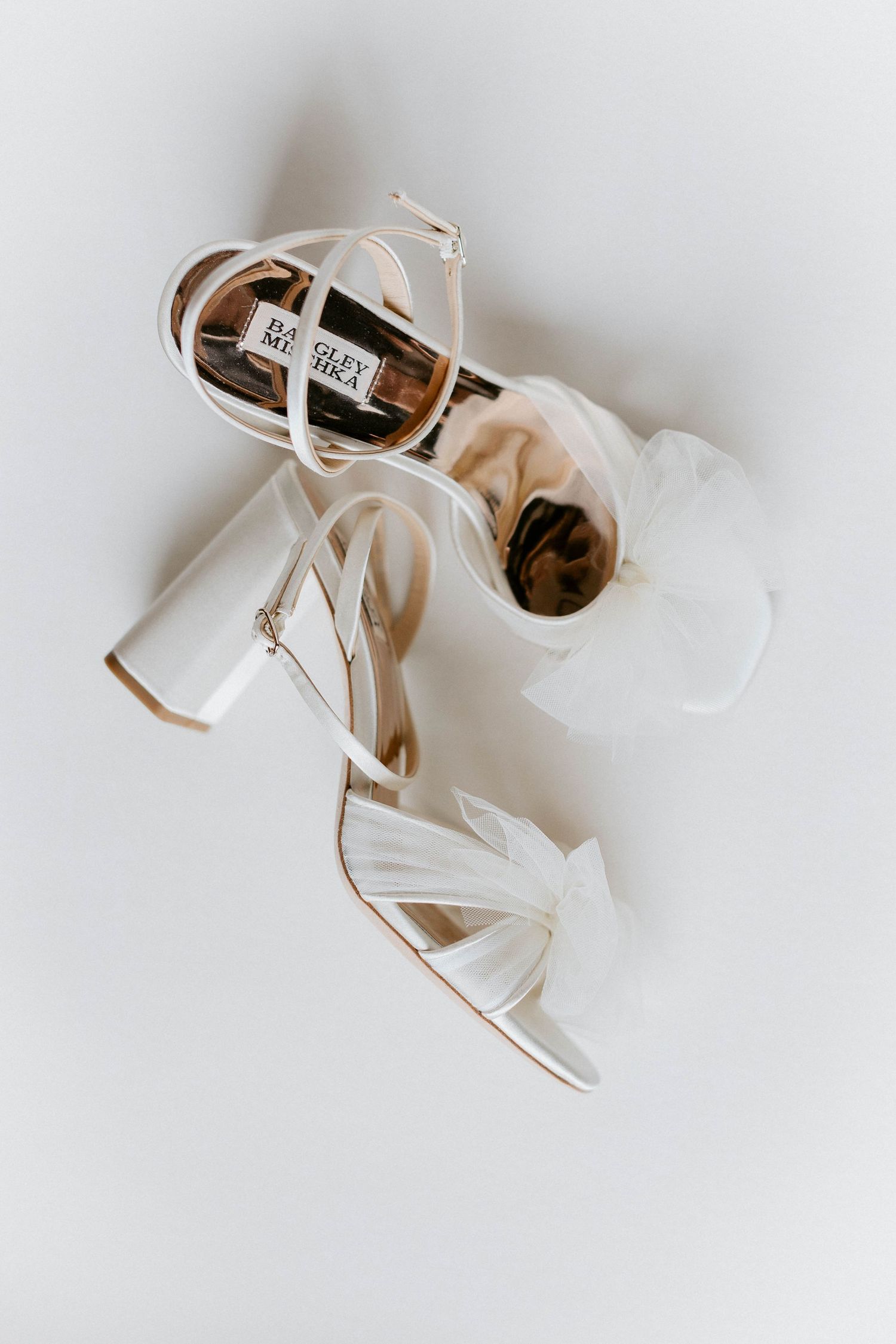 Elegant white wedding heels photographed on a light background.