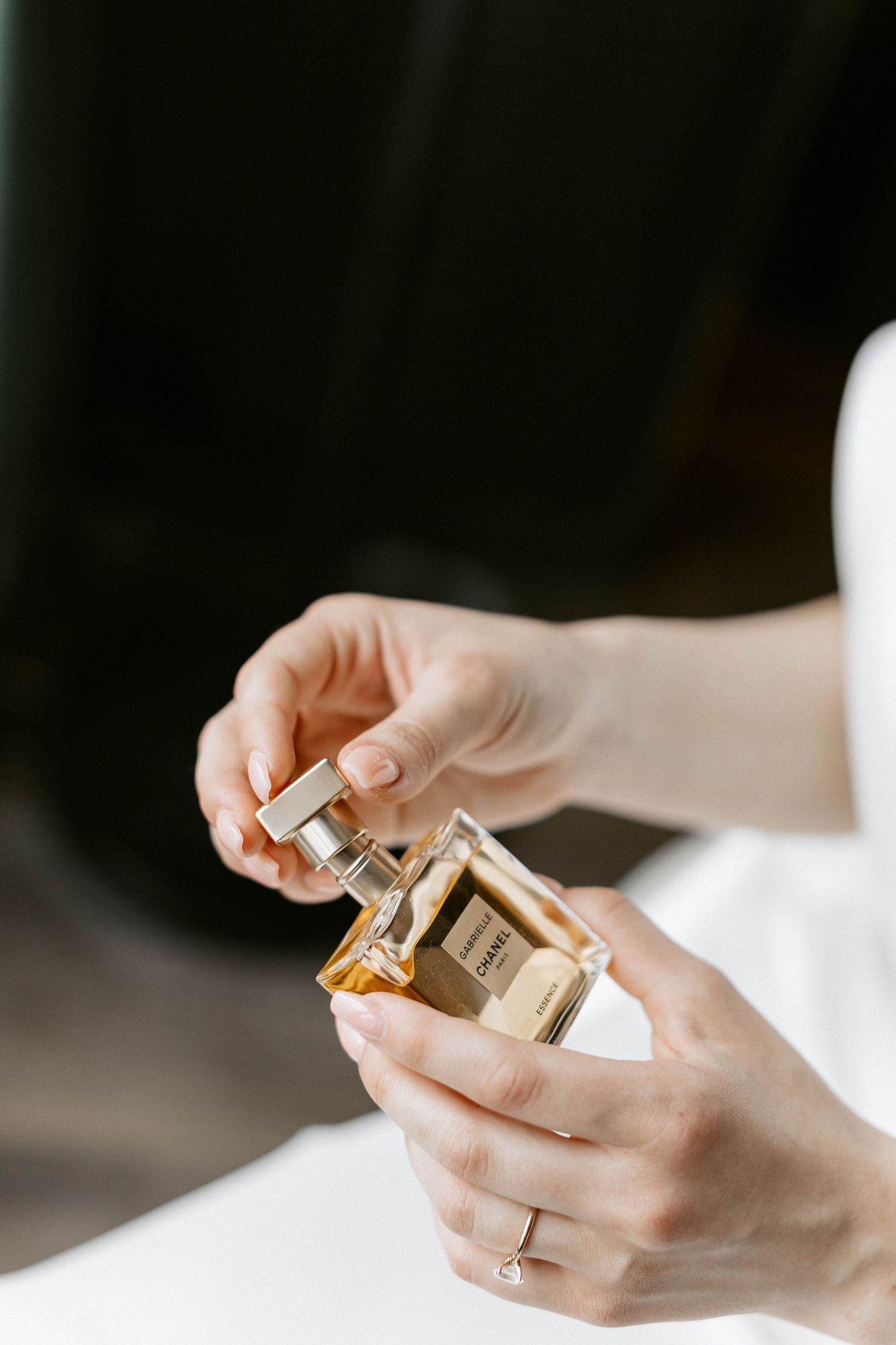 Hands holding a luxury perfume bottle against a white background.