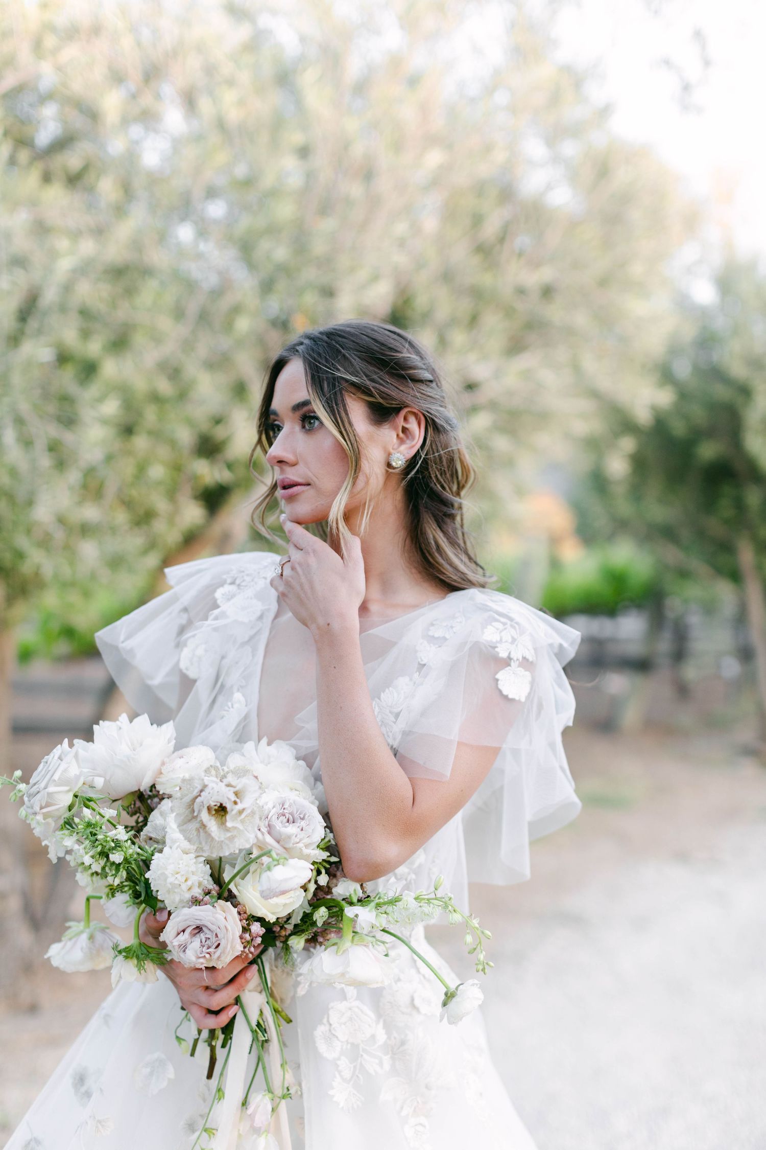 Ethereal bridal portrait with flowing veil and white bouquet in soft natural light.