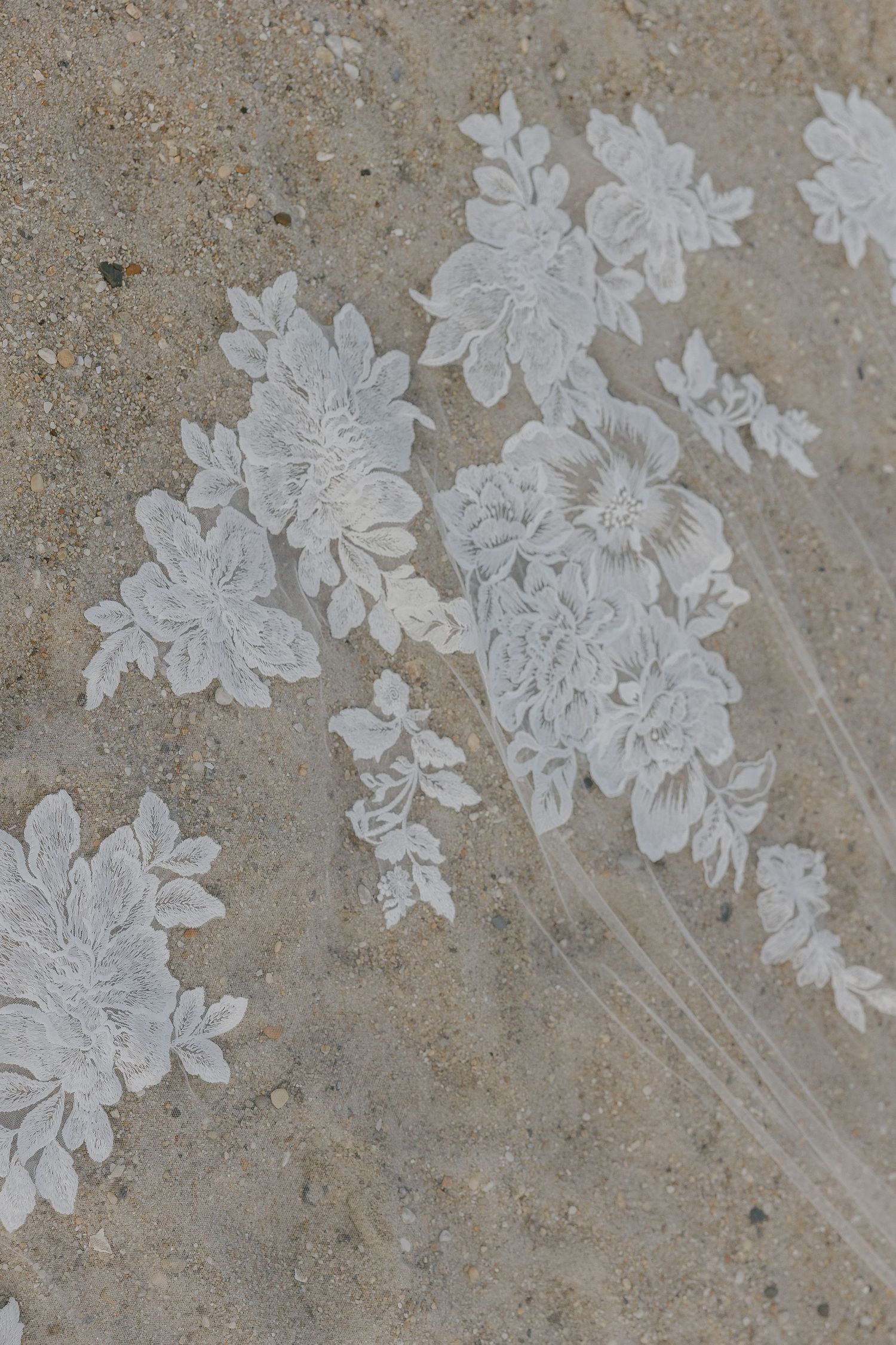 Delicate white floral lace appliques arranged in a row against a textured beige background.