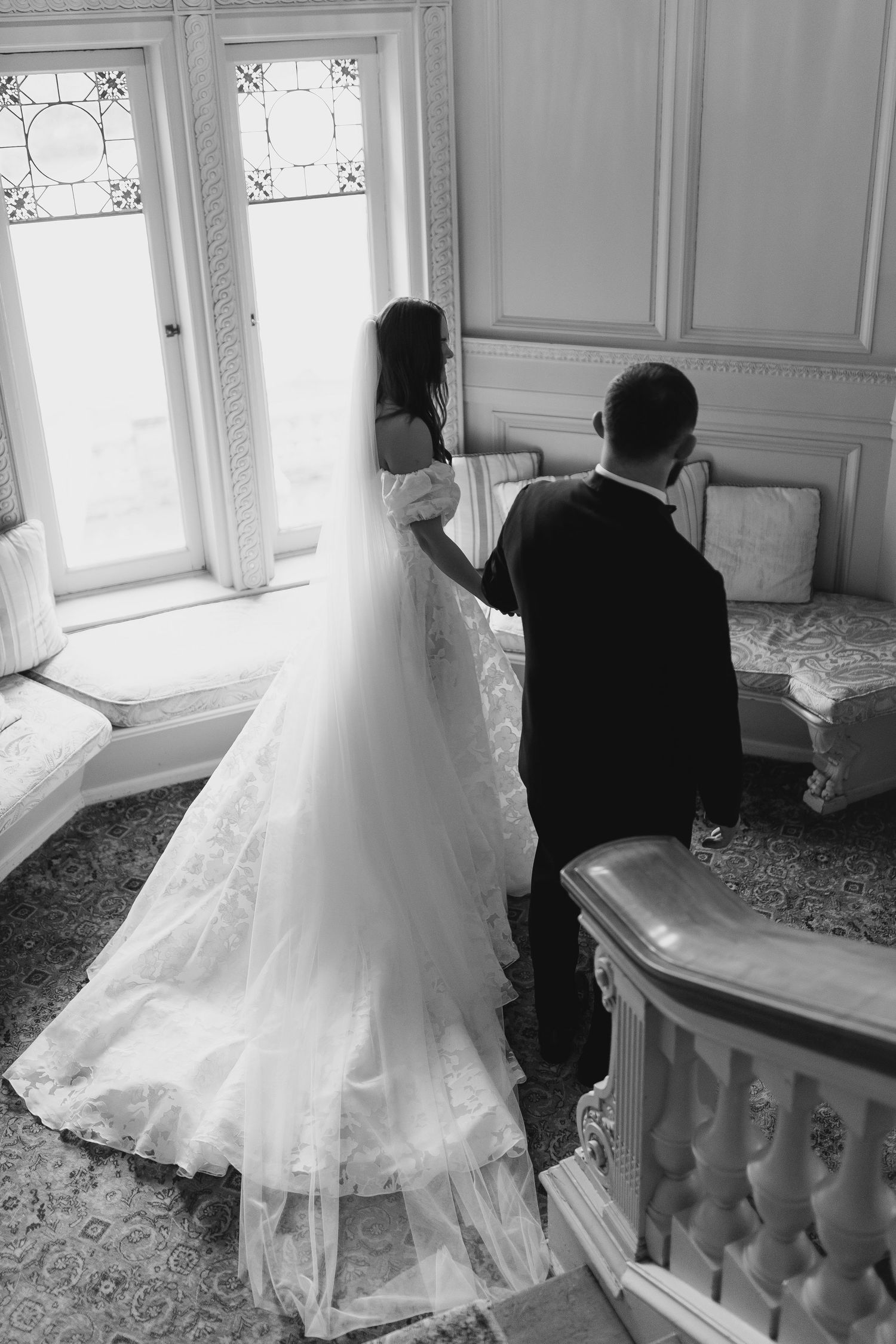 A black and white photo of a bride and groom ascending an ornate staircase.