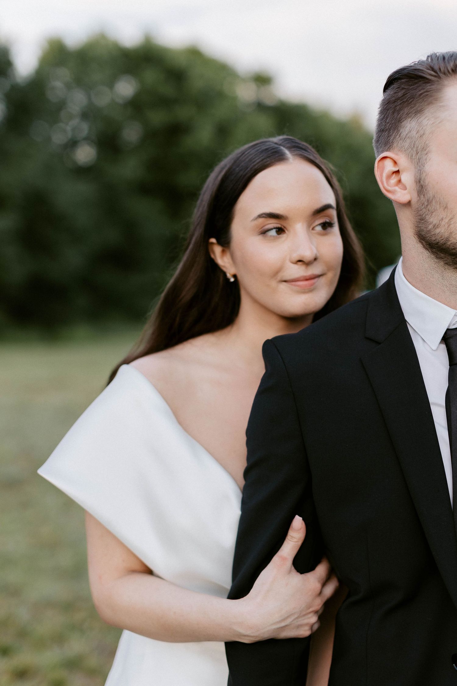 Candid wedding moment captured in a natural outdoor setting with elegant attire.